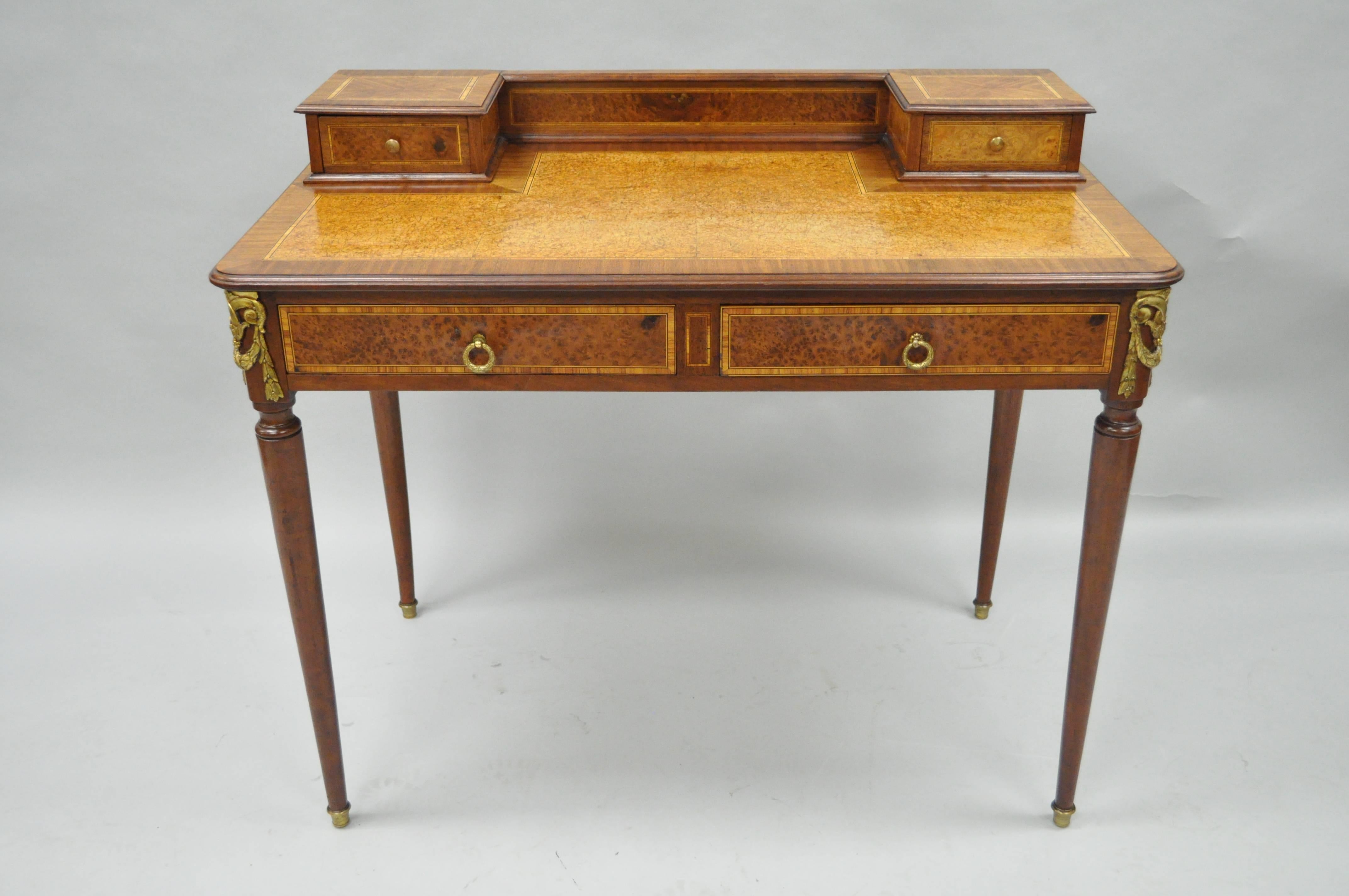 Early 20th century petite French Louis XVI style ladies writing desk. Item features a mahogany wood frame with bird's-eye maple and satinwood banded inlays, cast bronze drape form ormolu and hardware, and elegant French form. Table further features