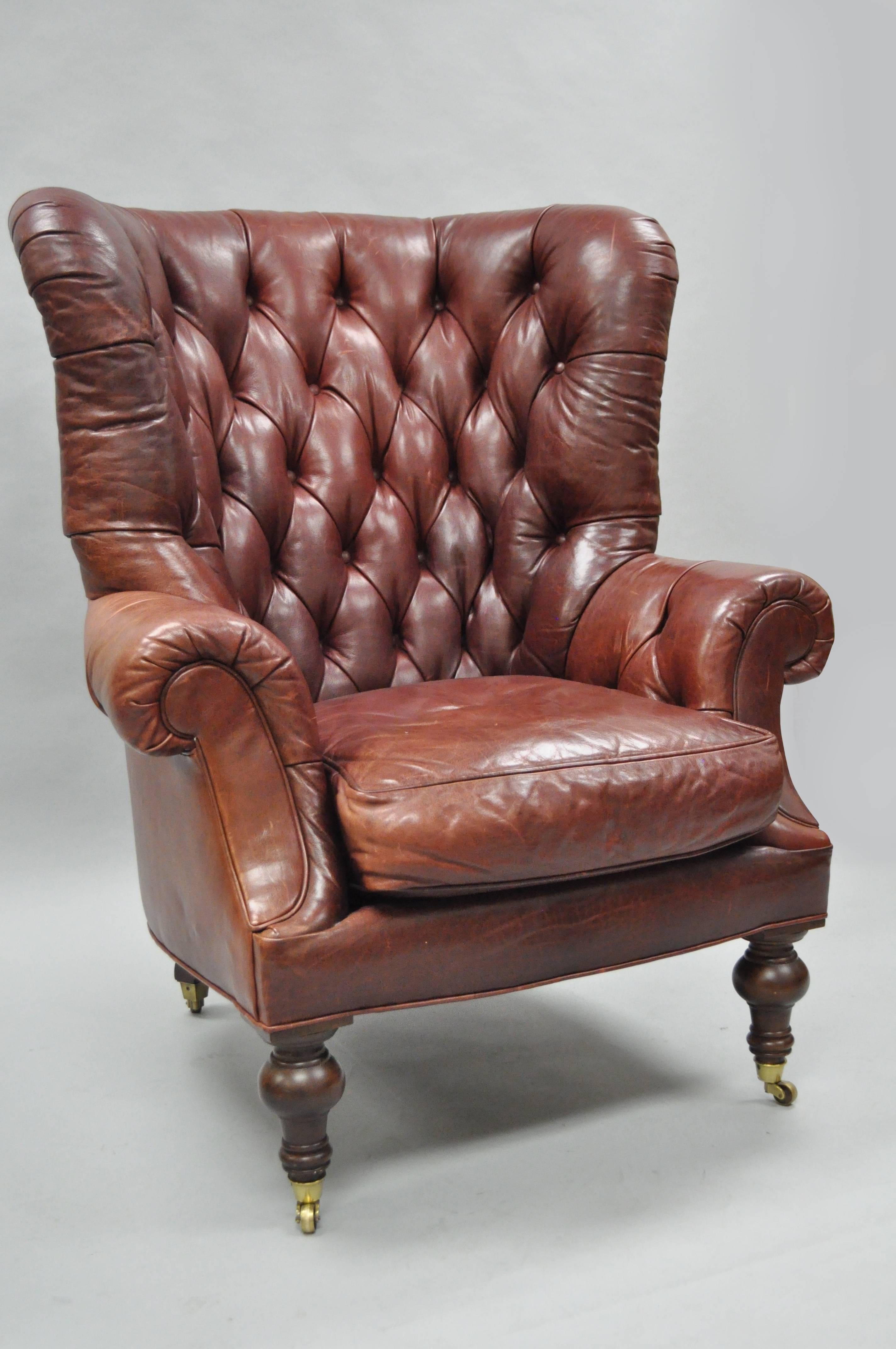 Quality 20th century oversized brown tufted leather English Chesterfield style lounge armchair by Lillian August. This remarkable item features a large stately solid wood wing back frame, button tufted leather upholstery, turn carved wooden legs