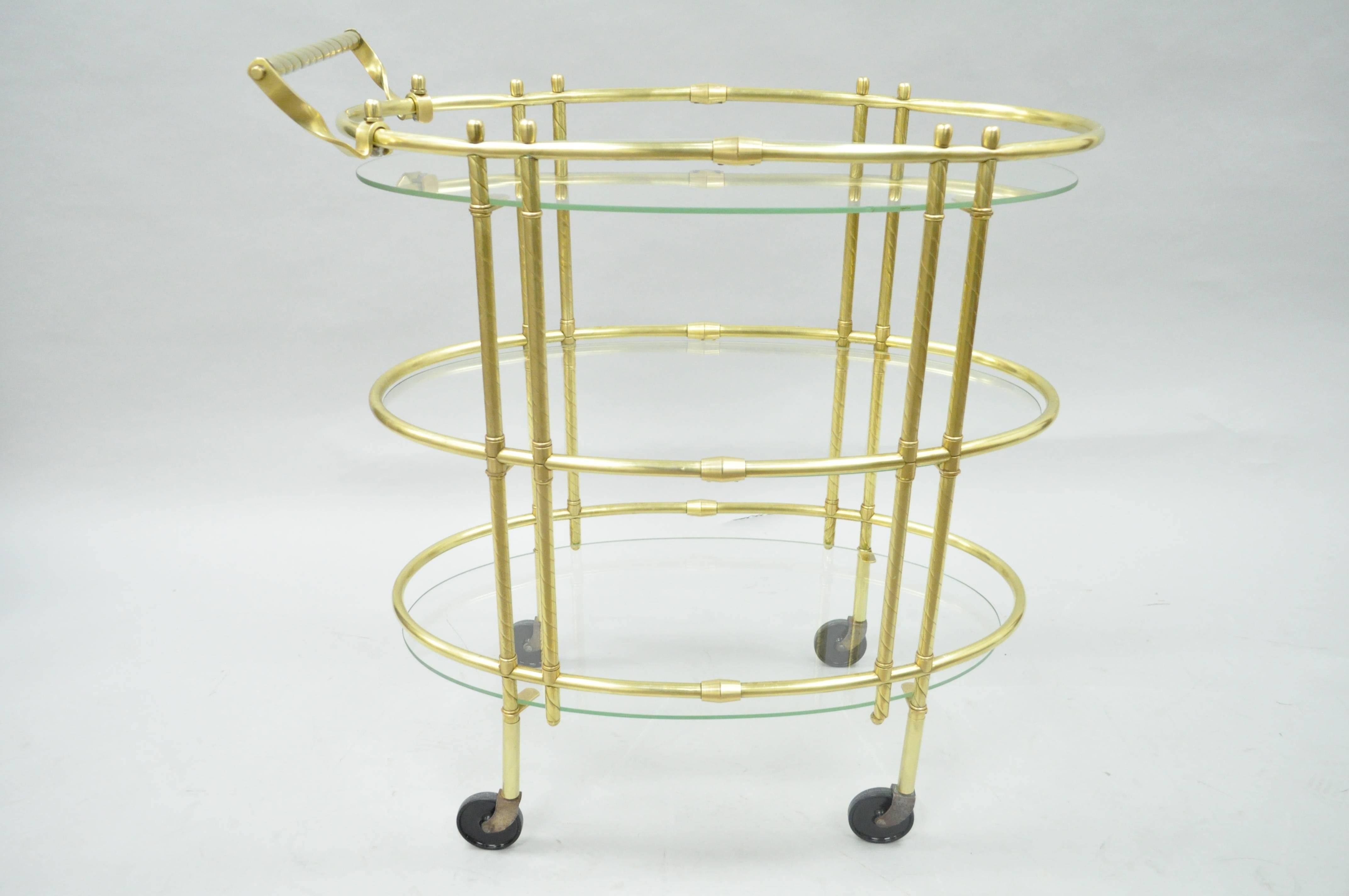 Vintage Mid-Century Italian Modern polished brass three-tier oval bar or tea cart. Item features a polished brass frame, oval floating form glass shelves, rolling casters, spiral turned handle, great Modernist form.