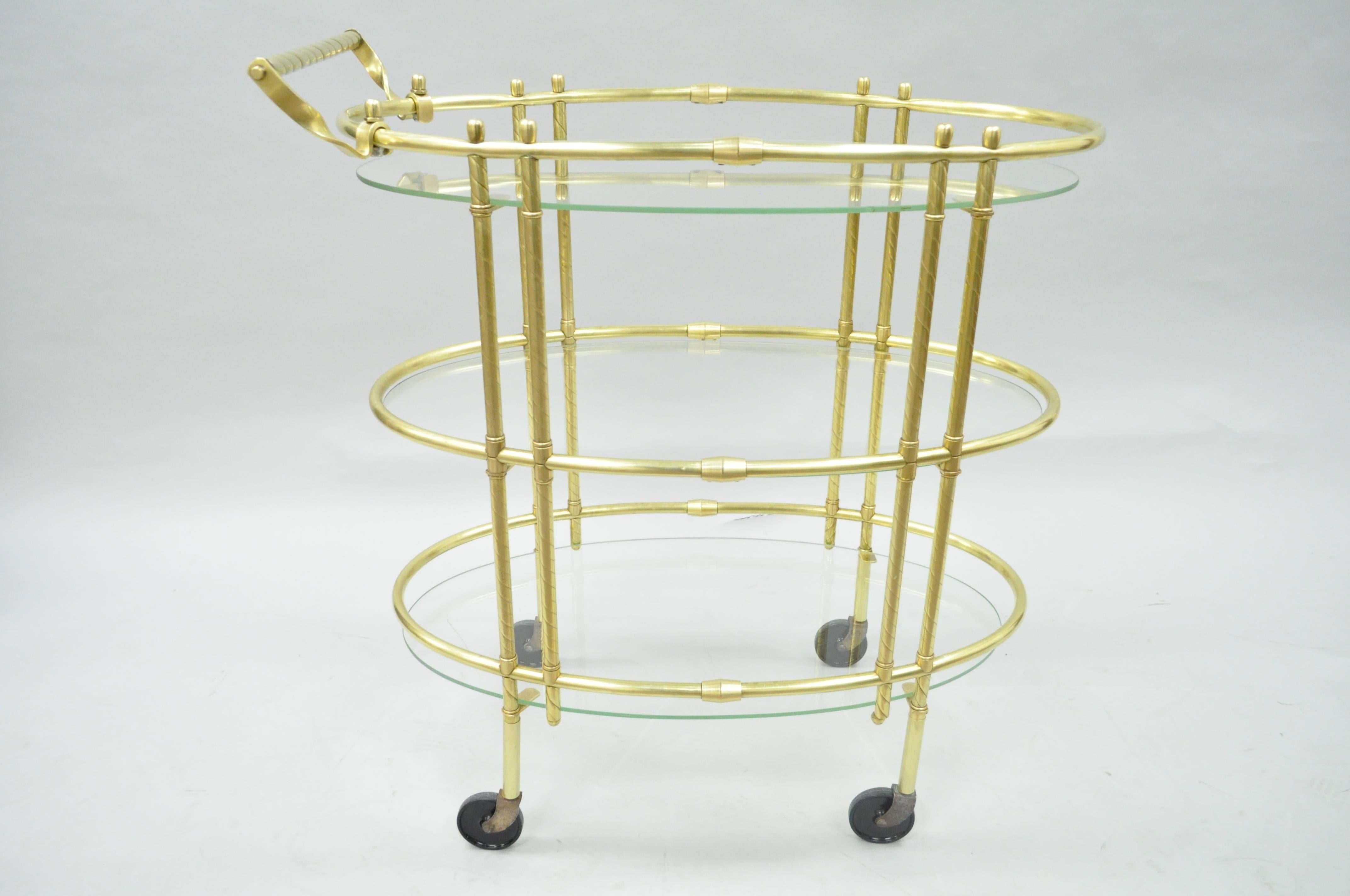 Carrito de bar o de té ovalado vintage de latón pulido de la Modernidad italiana de mediados de siglo. El artículo presenta un marco de latón pulido, estantes ovalados de cristal de forma flotante, ruedas giratorias, tirador torneado en espiral, de