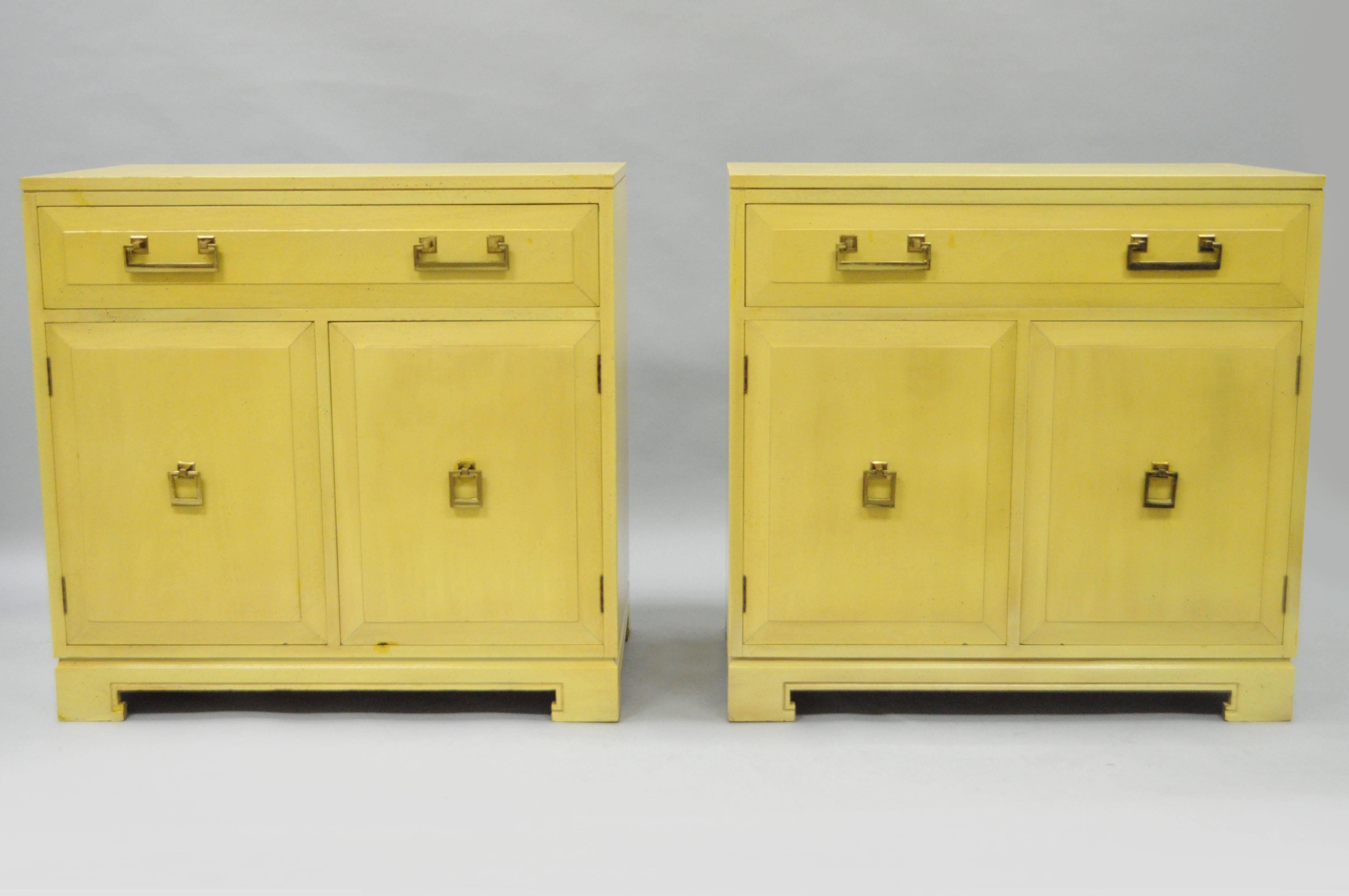 Pair of vintage Mid-Century American Modern / Hollywood Regency yellow mahogany cabinets by Rockford National Furniture Co. of Rockford, IL. The pair features the original yellow painted finish to the mahogany wood cases, polished brass drop pulls,