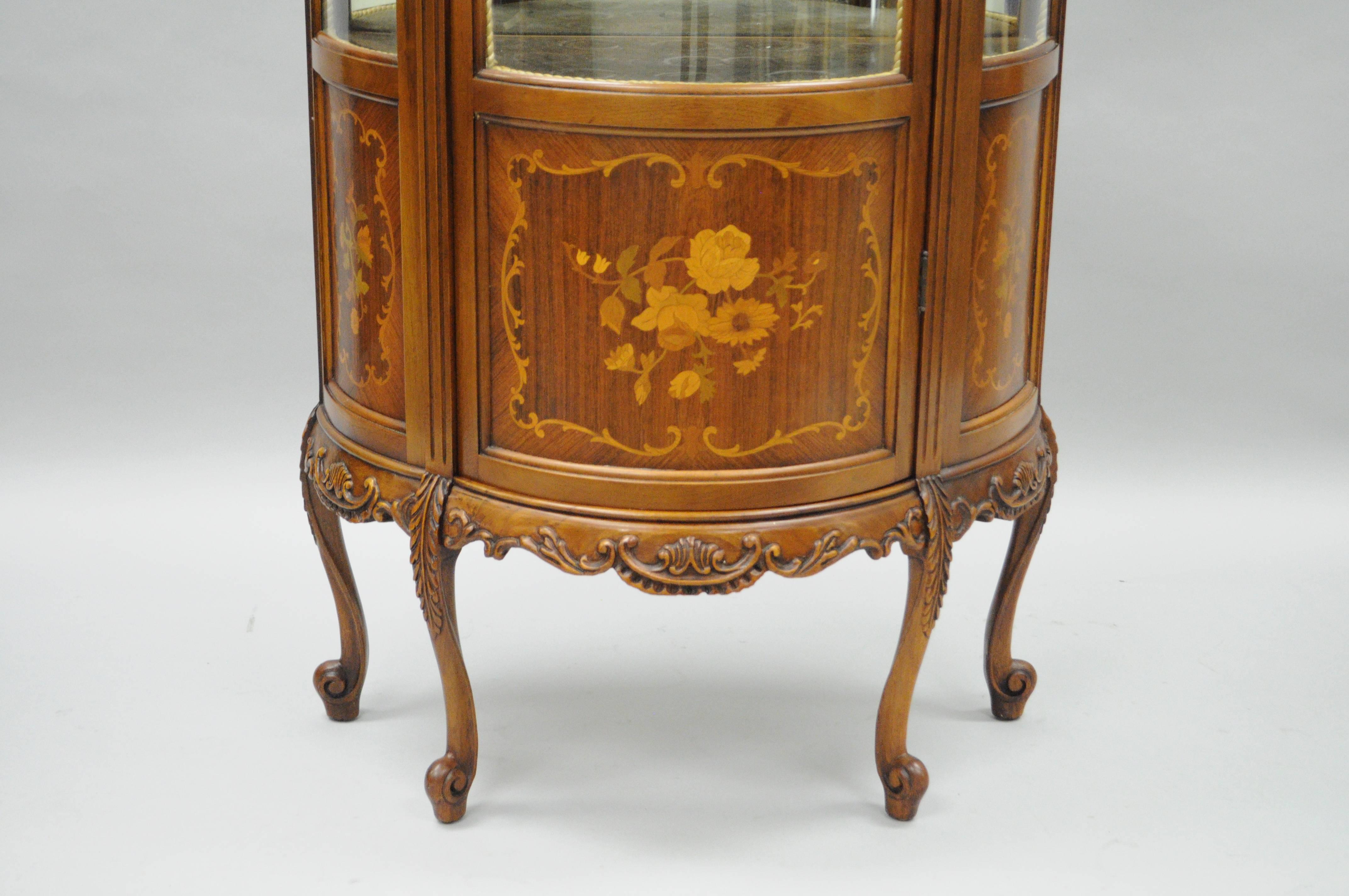 Vintage French Louis XV style demilune Curio cabinet. Item features a carved mahogany case with satinwood floral inlays, three curved glass panels, mirror glass interior backing, two curved glass shelves, single swing door with working lock and key,