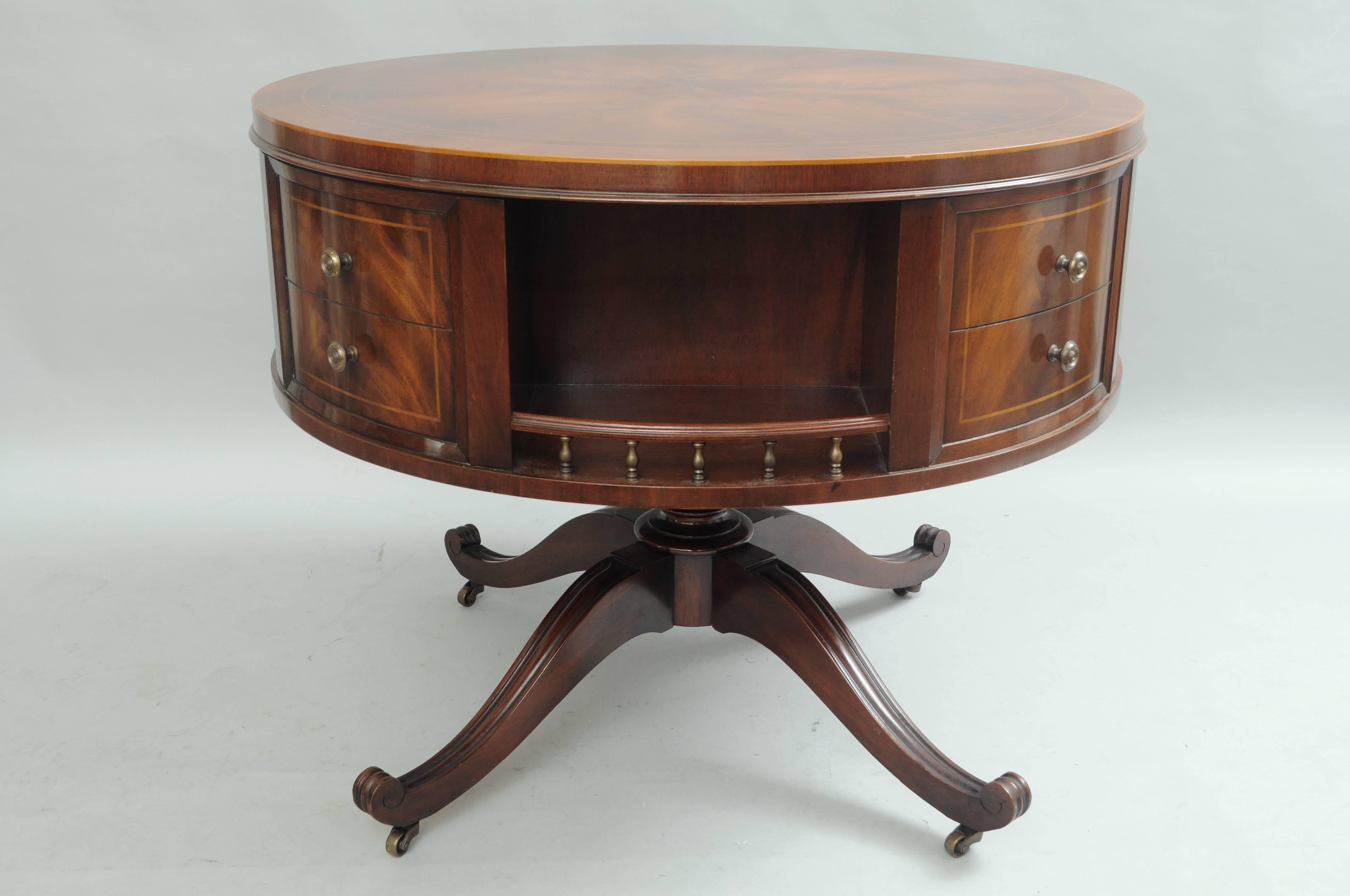Early 20th century revolving/rotating Regency style mahogany drum/center table. Item features a beautiful sunburst top with banded and inlaid detailing, brass pulls, faux drawers, spinning center with cubby storage, pedestal base and rolling