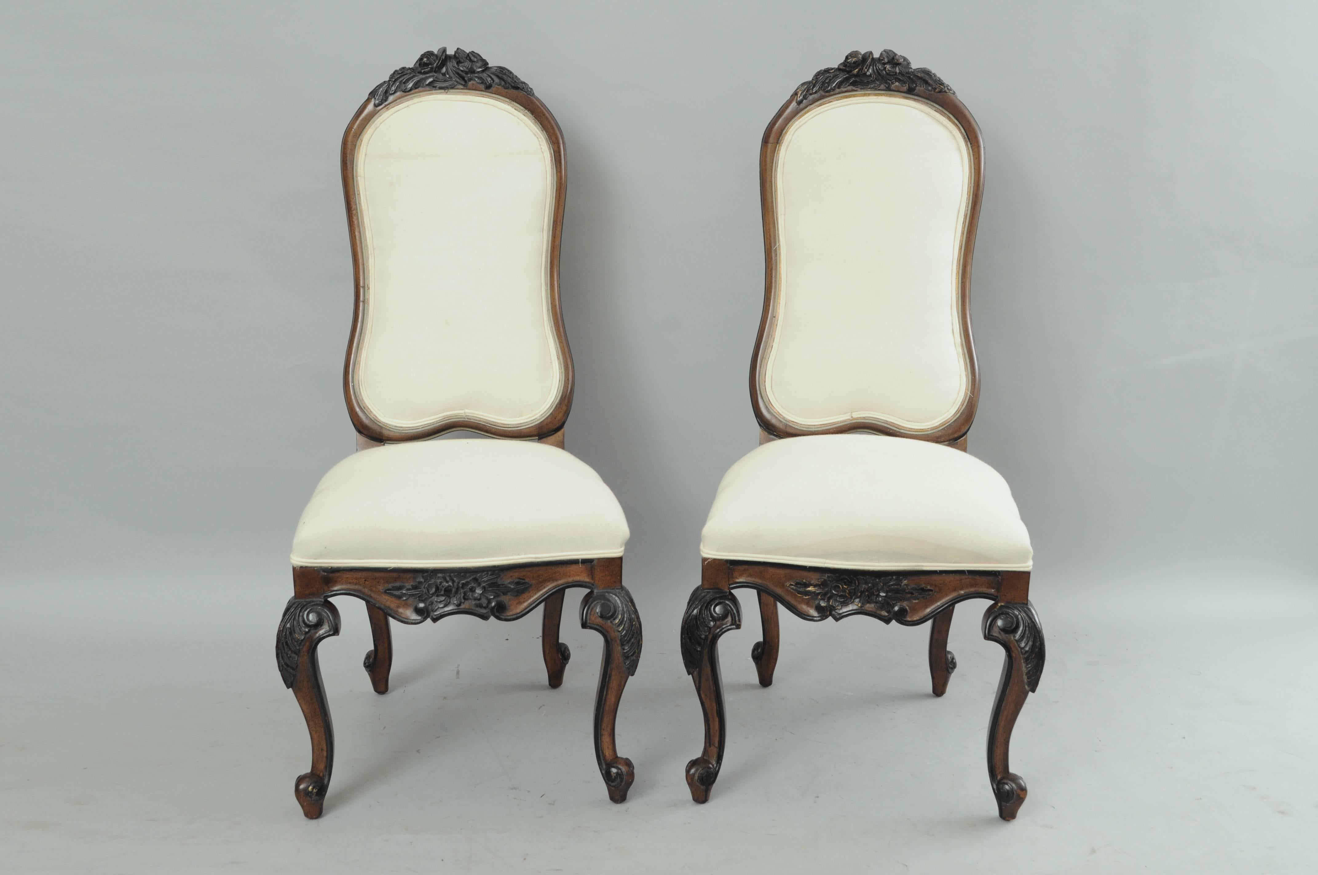 Set of eight Vintage French Country / Italian Baroque style upholstered high back dining room chairs. This set of eight chairs features high quality solid carved wood frames, black distress painted floral accents at the crest, knees and rail. Chairs