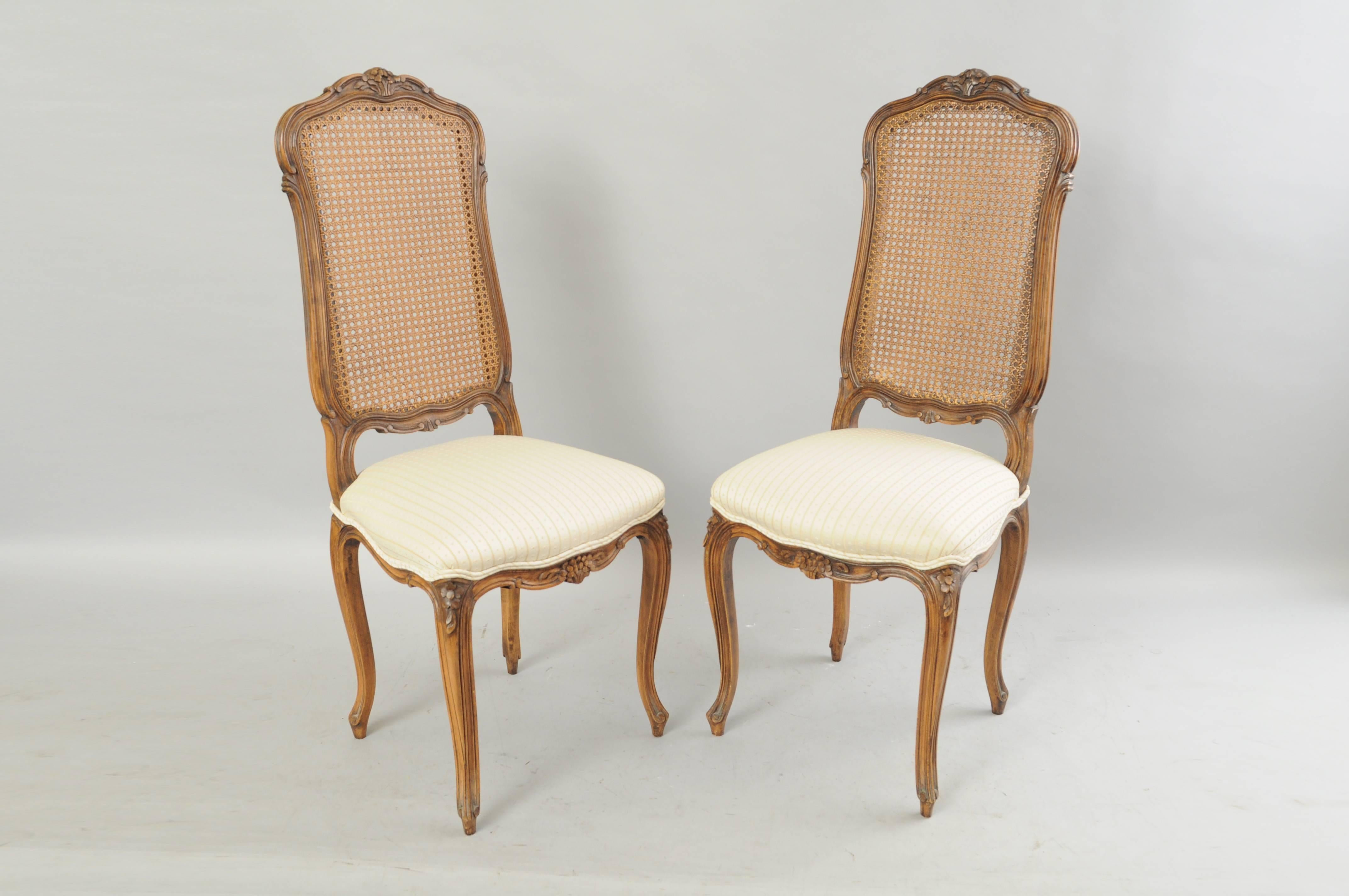 Quality set of six vintage French country / Louis XV style tall cane / rattan back solid walnut dining chairs. The set features elegant narrow frames, carved crests and rails, cabriole legs, cane backs, upholstered seats, and great quality and form.