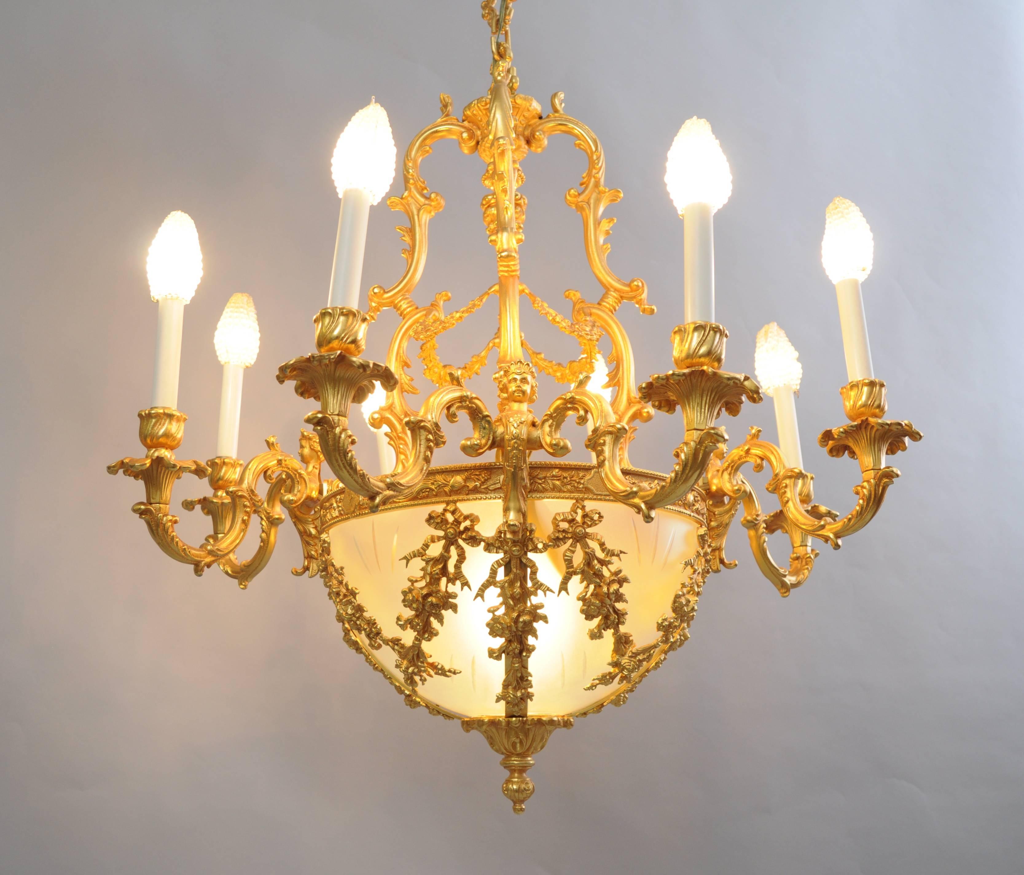 Remarkable quality 20th century Italian doré bronze French Rococo / Louis XV style figural gold chandelier, Made in Italy. Item features adorable angels / cherub accents, draped floral, acanthus leaf, and ribbon decoration, 8 arms, and an etched