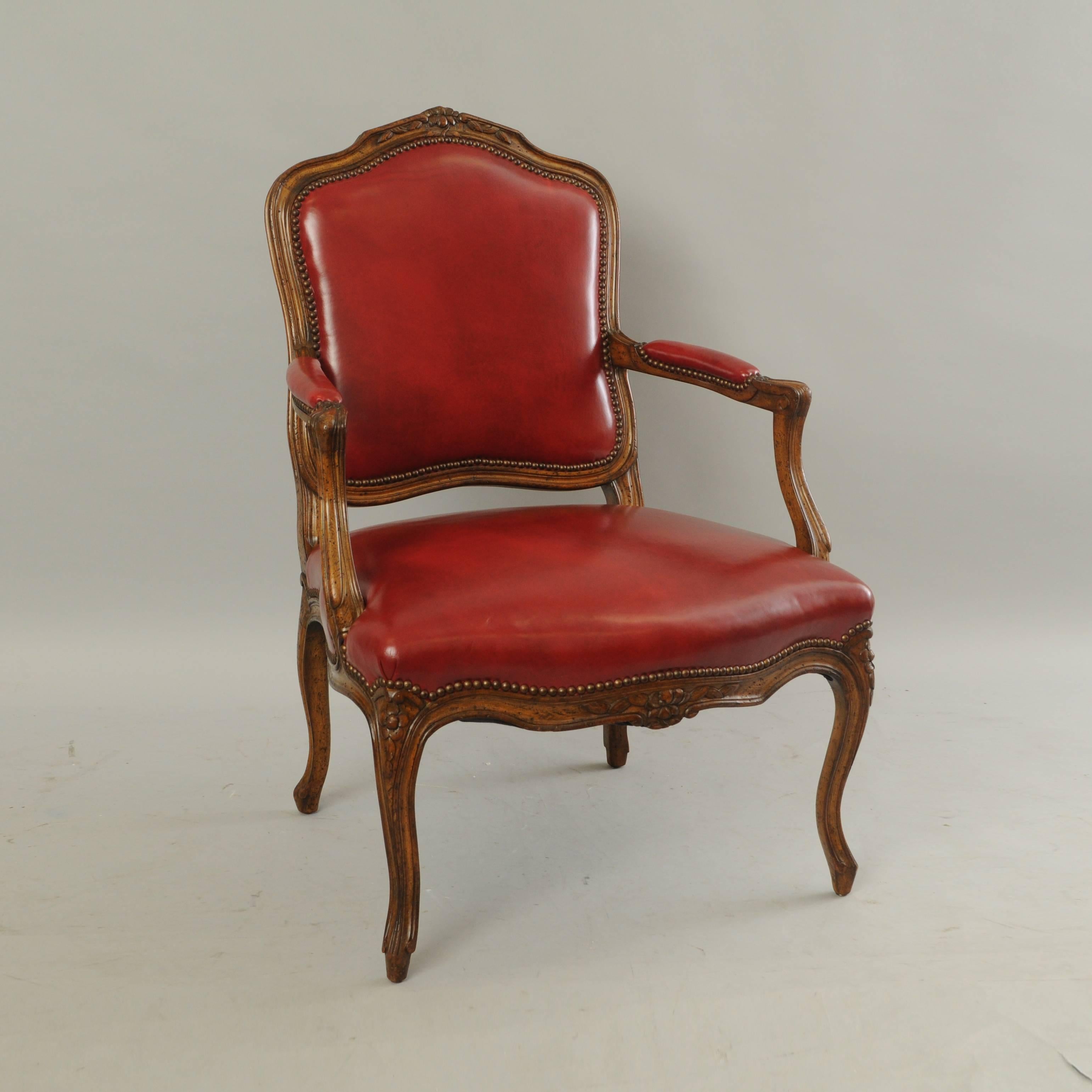 Vintage French Country/Louis XV style armchair in walnut and red leather by Auffray & Co. Item features a solid carved wood frame, red leather upholstery, nailhead trim, cabriole legs, antiqued/distressed finish, original label to underside, great