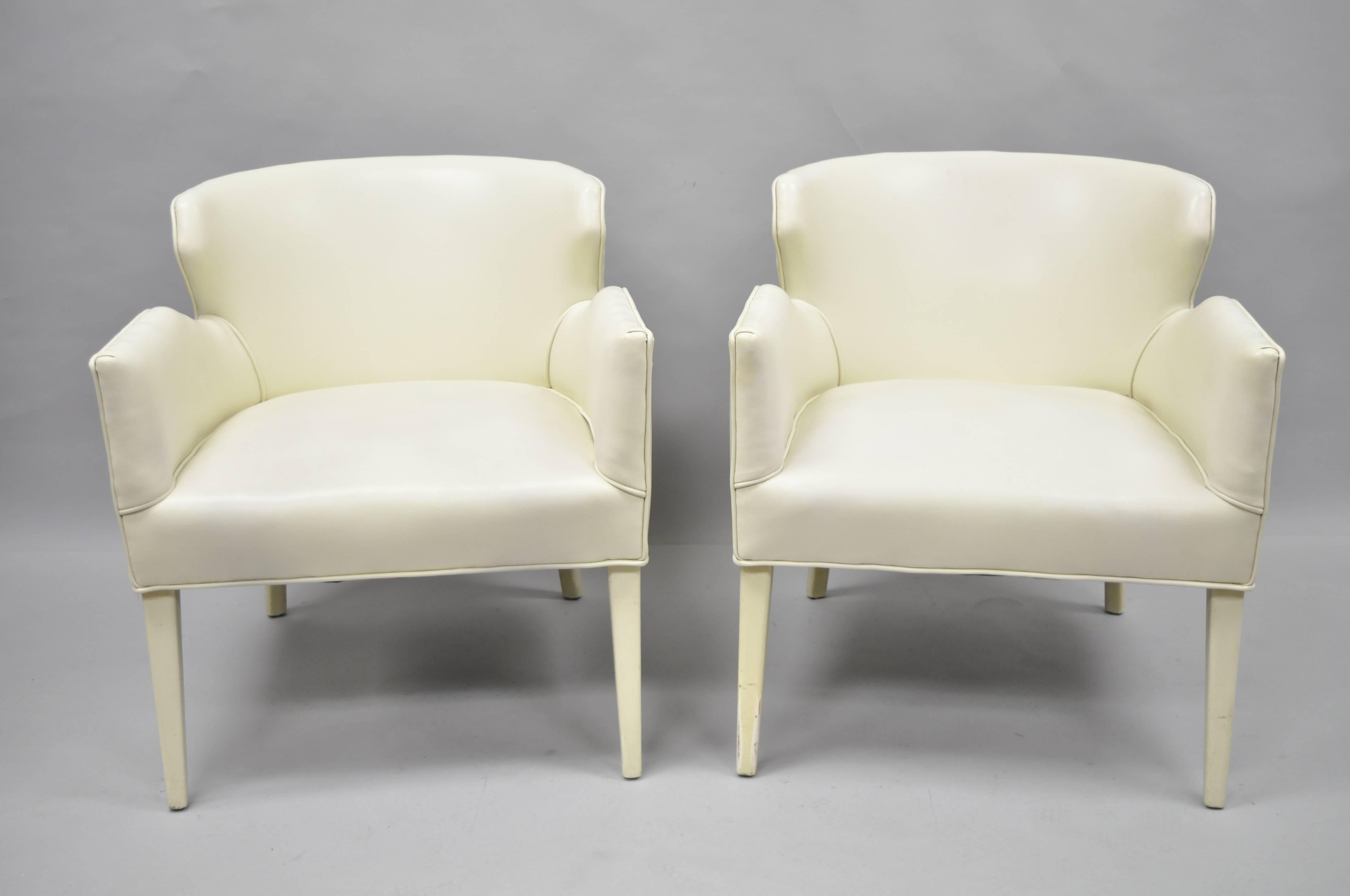 Pair of vintage Mid-Century Modern sculptural club chairs in the manner of Paul McCobb and Harvey Probber. The pair features shapely barrel backs, heavy solid frames, nice deep seats, angled arms, off white vinyl upholstery and off-white tapered