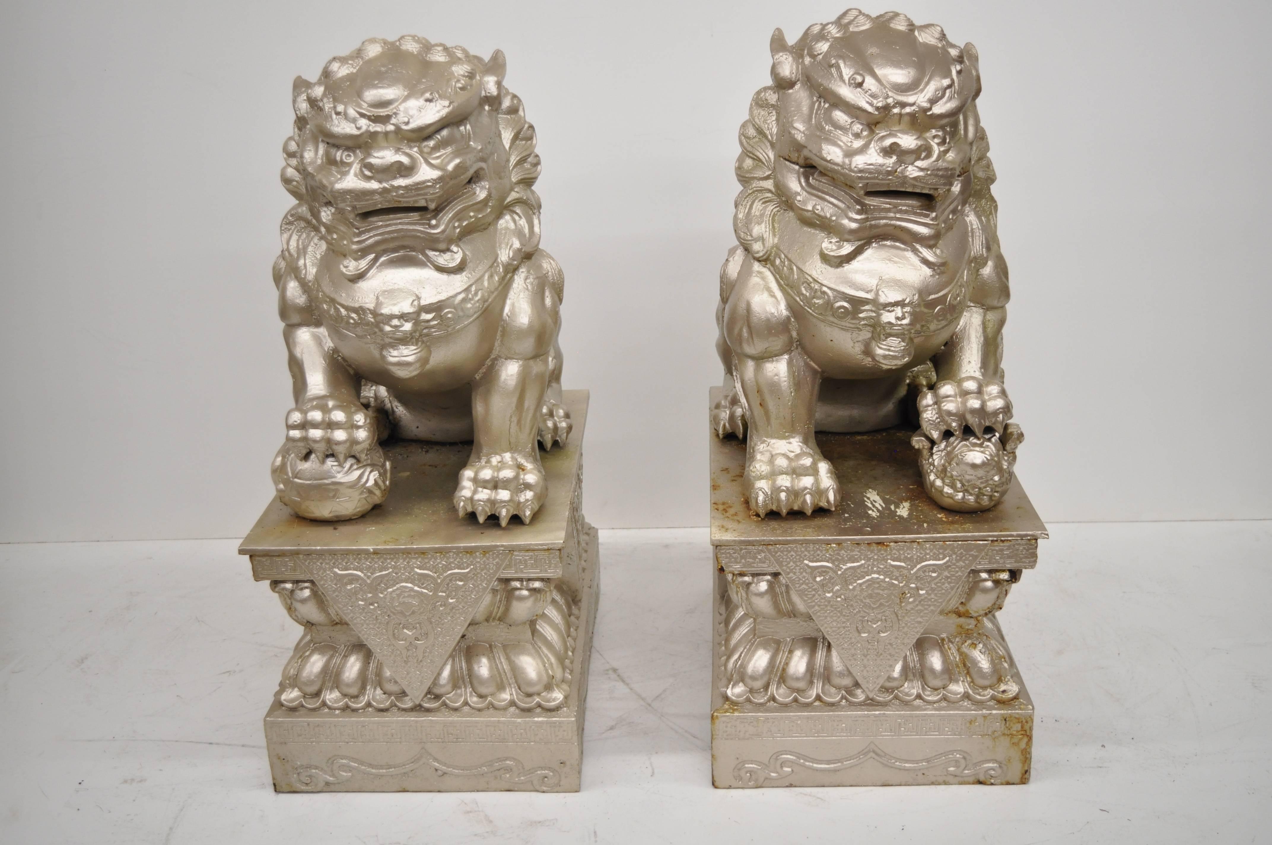 36" tall pair of stately cast iron Chinese foo dog guardian pedestals. The pair features right and left foo dog forms resting on affixed pedestal bases, heavy cast iron construction (weighing approx 250 pounds each), silver metallic weathered