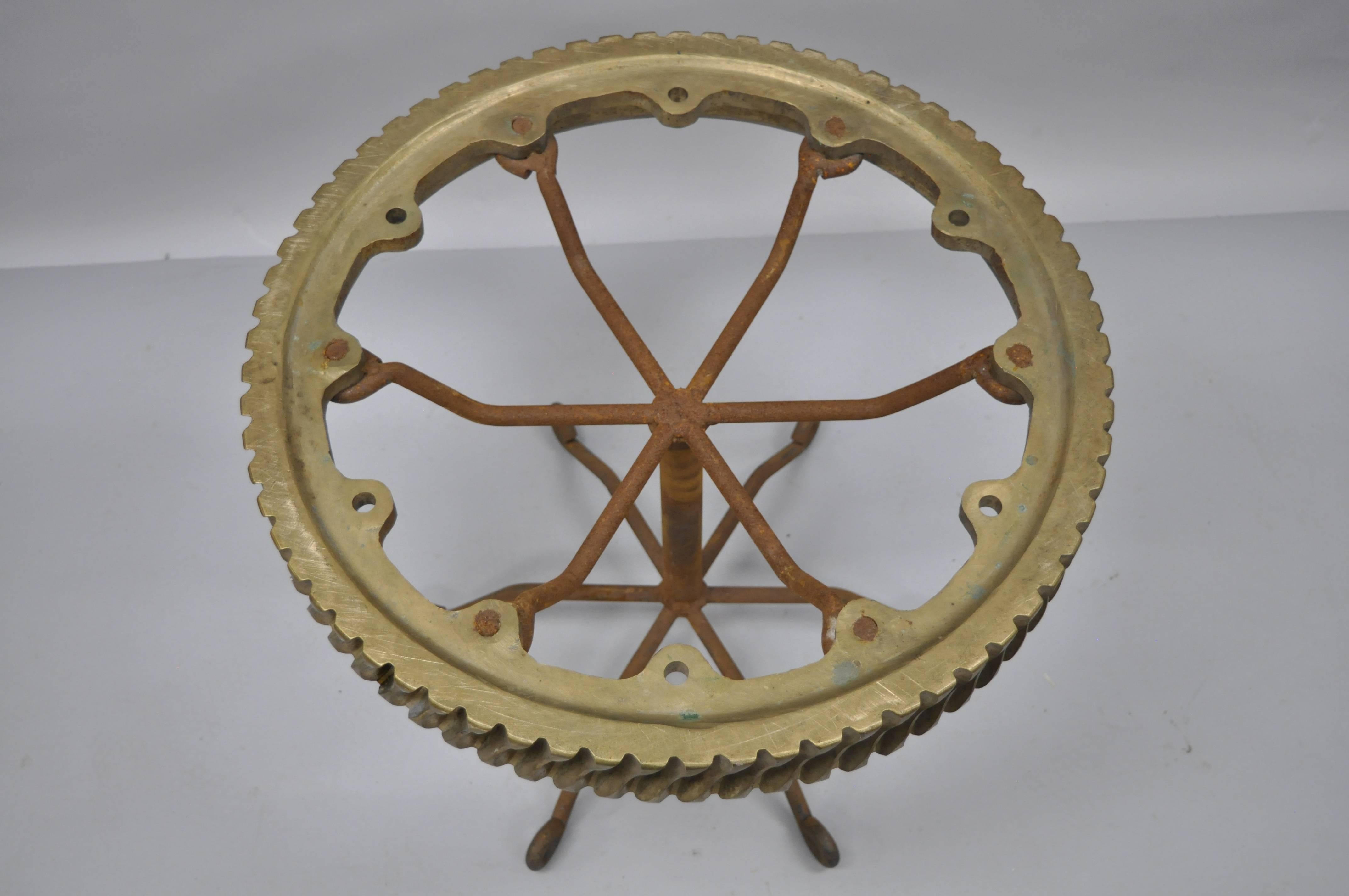 Vintage Brutalist artisan crafted bronze elevator worm gear table on iron spider leg pedestal base. This Industrial table features an authentic antique/vintage bronze elevator gear with wonderful aged patina welded to a scrolling spider leg base.