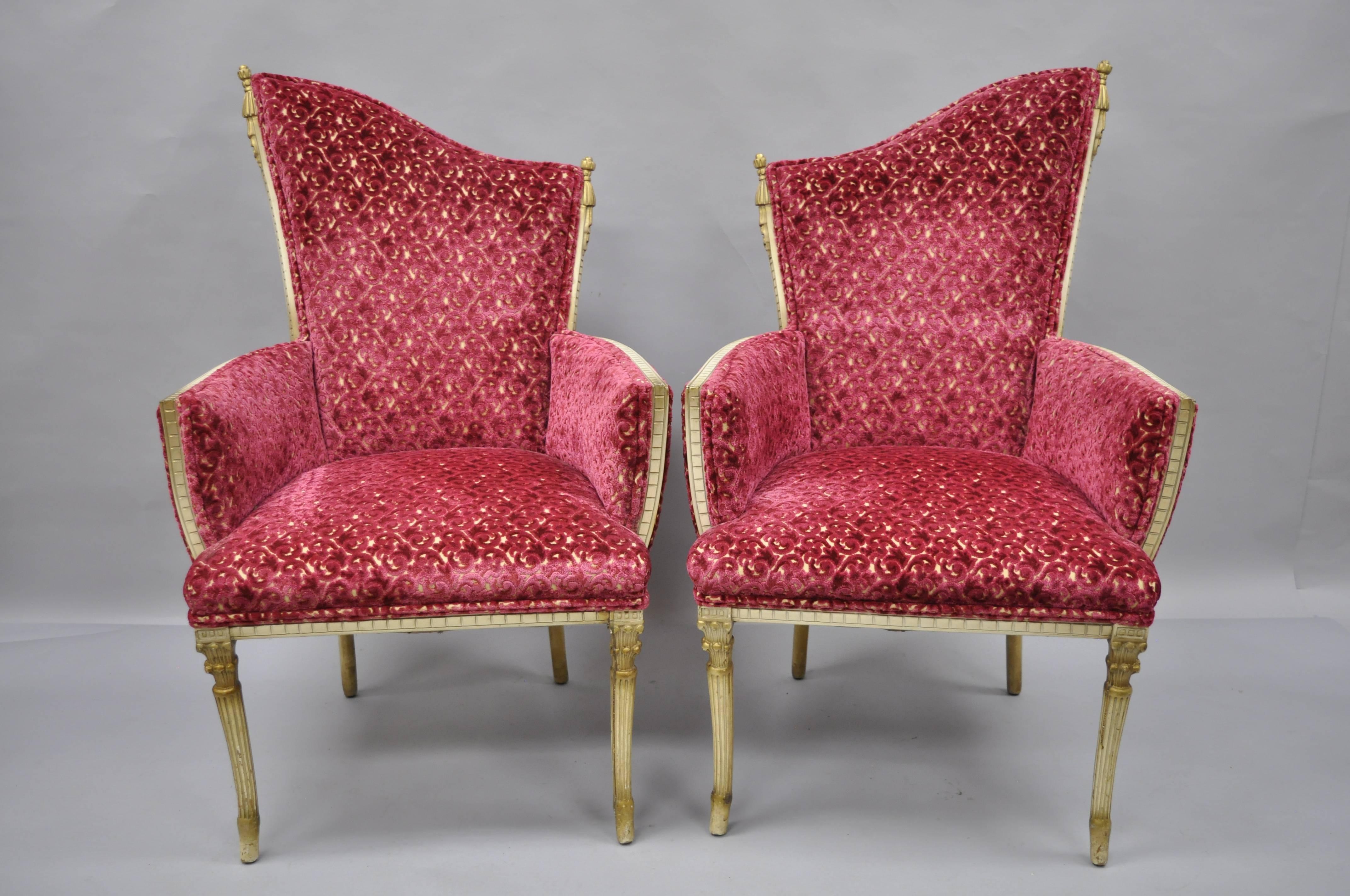 Pair of vintage Hollywood Regency French style carved tassel armchairs in the Dorothy Draper style. Item features solid wood construction, nicely carved tassel details, tapered legs, cream and gold painted finish, excellent reddish burgundy and