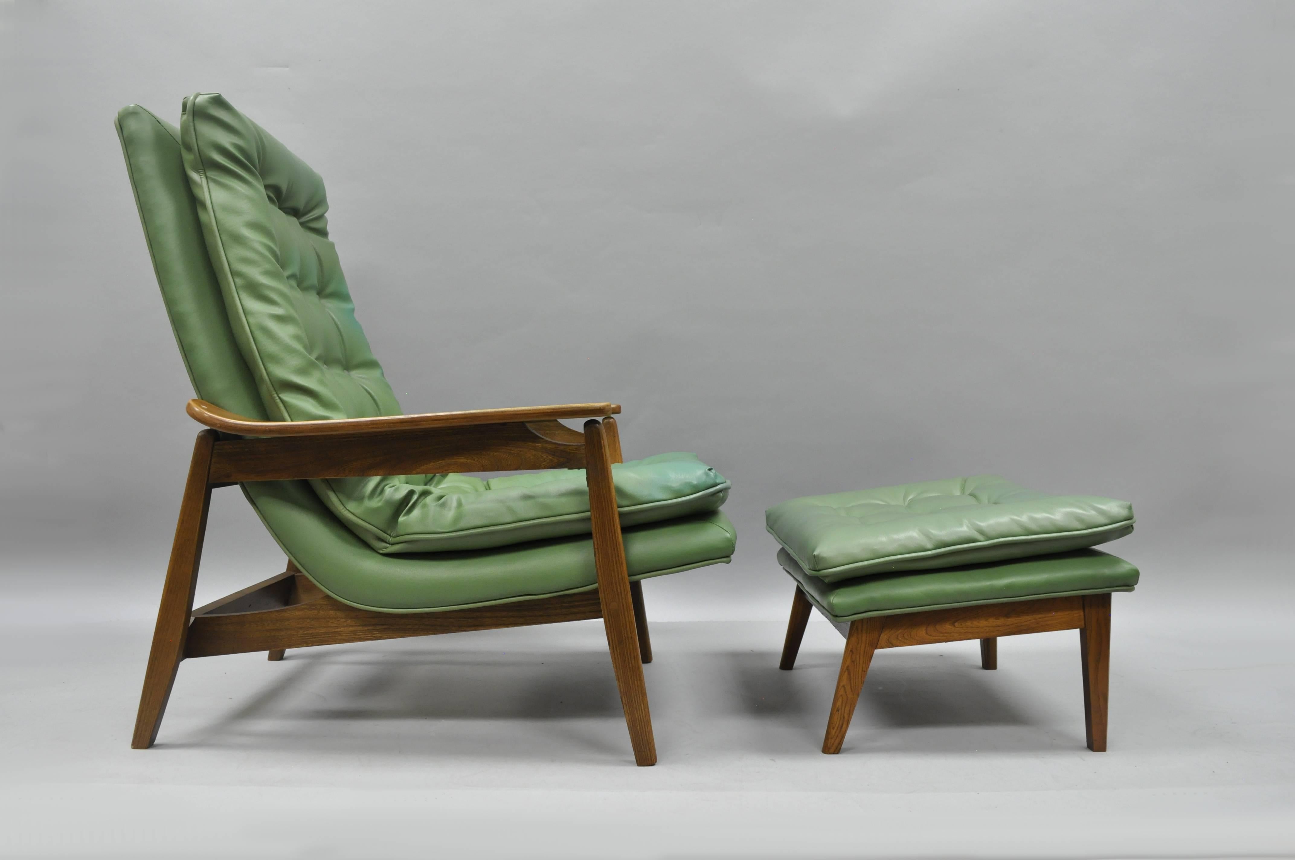 Vintage Mid-Century Modern walnut lounge chair and ottoman after Milo Baughman with original tufted green vinyl upholstery in the Danish modern style. Item features solid wood construction, sleek sculptural form, tall back lounge chair and original