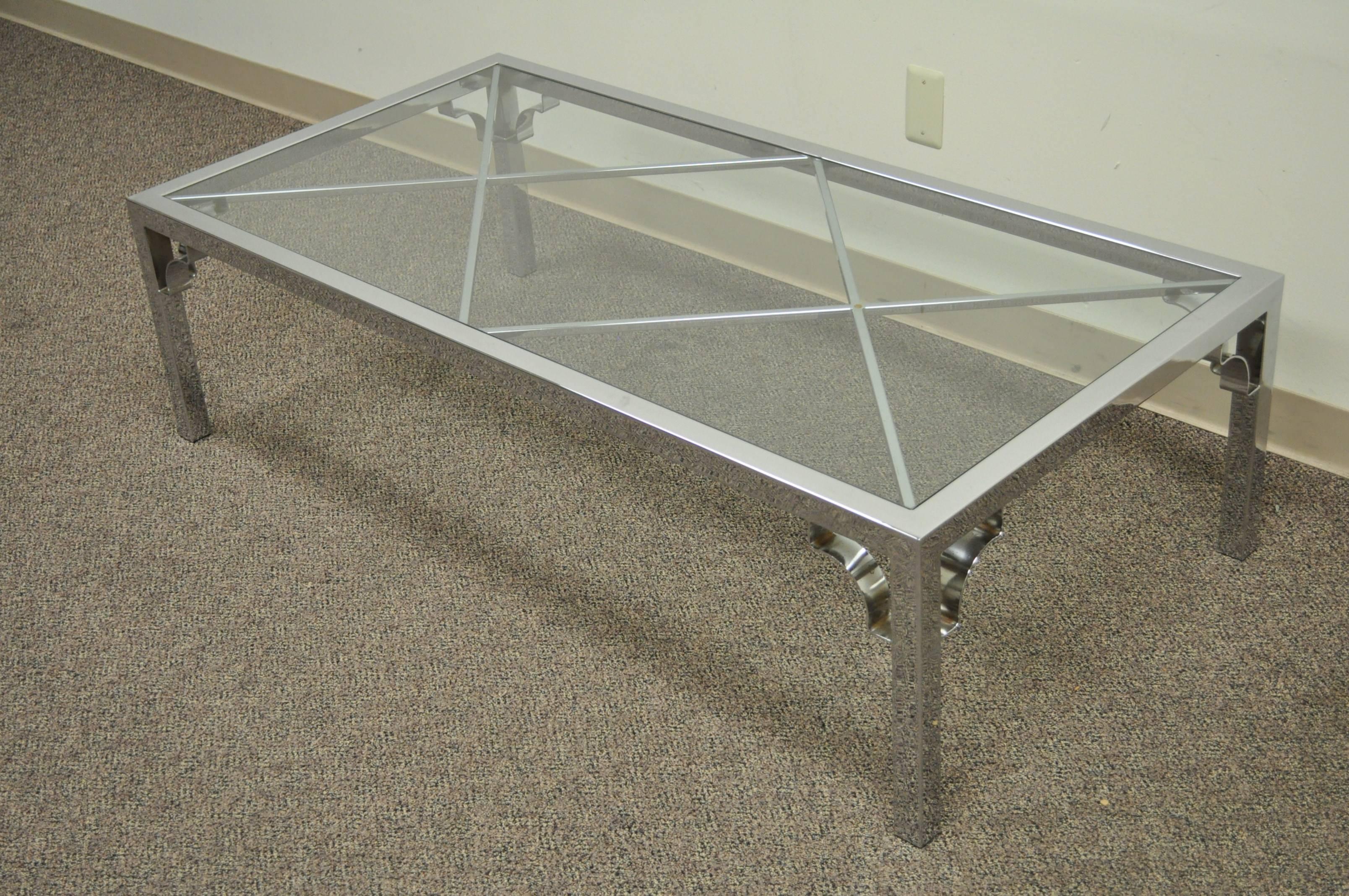 Wonderful vintage coffee table with polished chrome frame and double X-forms under the inset glass top. This table features polished seamless joints throughout for a more clean overall aesthetic. Each leg has decorative arched detailing at the