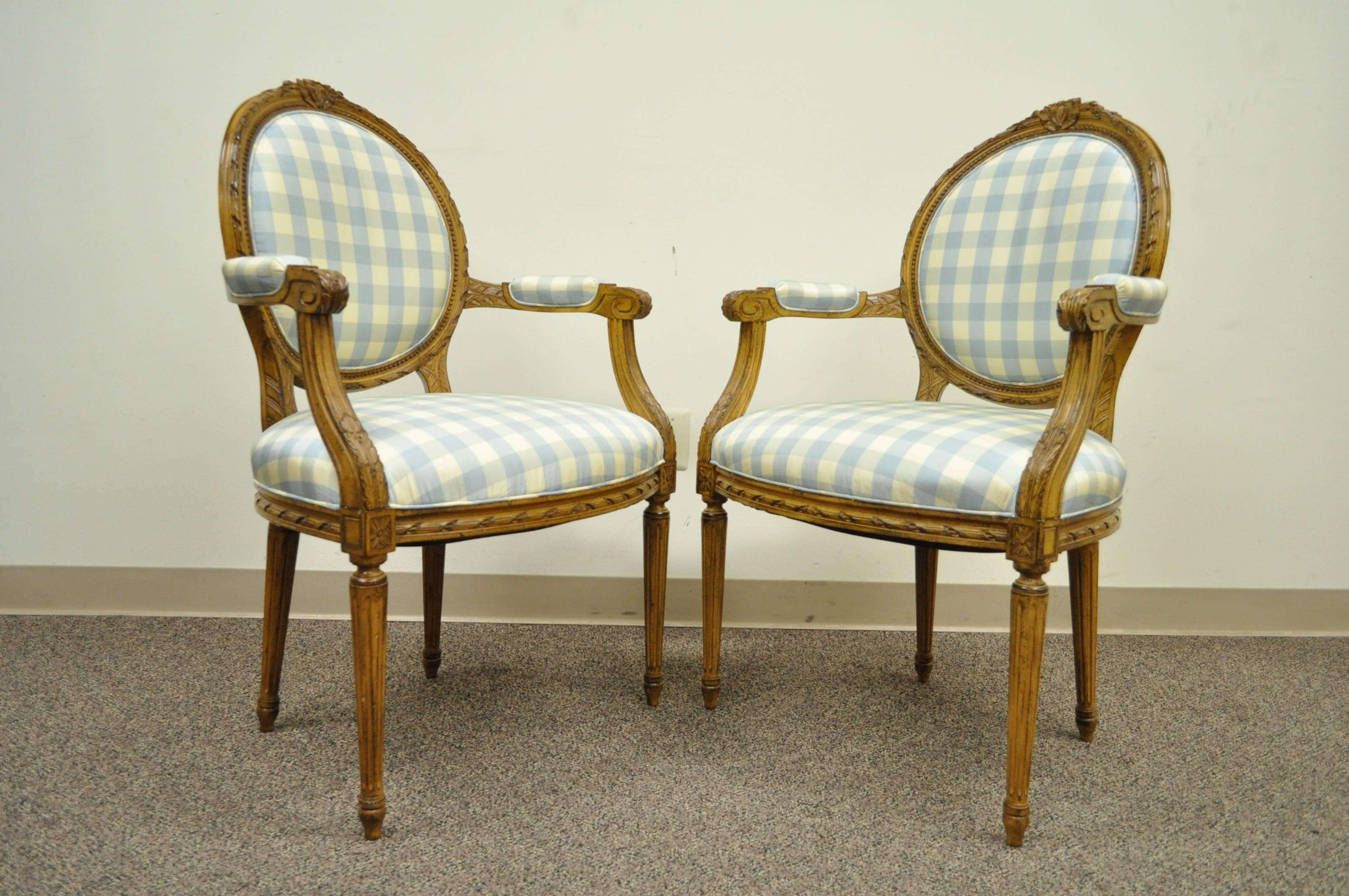 Quality pair of mid-20th century carved frame medallion back armchairs in the Louis XVI style. This classy pair features carvings throughout the frame including bow carved accents at the crest as well carvings to the medallion backs, skirts and