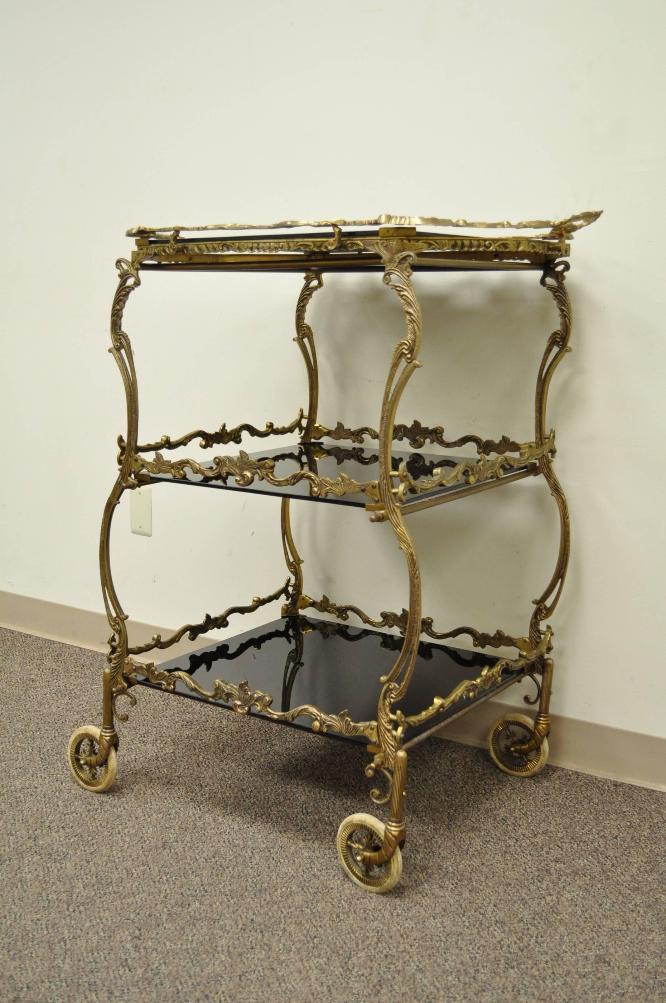 Stunning French three-tier dessert cart. Item features an ornate brass frame with black vitrioled glass surfaces and a removable serving tray on the top tier. Item can be used as a bar table/trolley or tea cart as well.