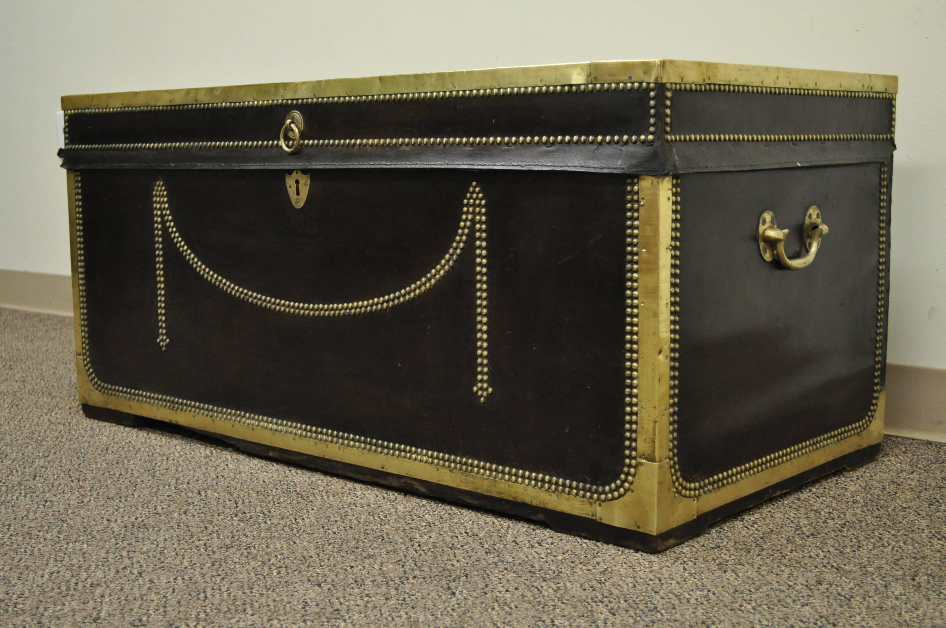 19th century handmade leather and brass-clad trunk over camphor wood. Item features strips of brass trim as well as decorative brass nailheads adorning the chest. Would work wonderful as a coffee table or decorative object in any setting.