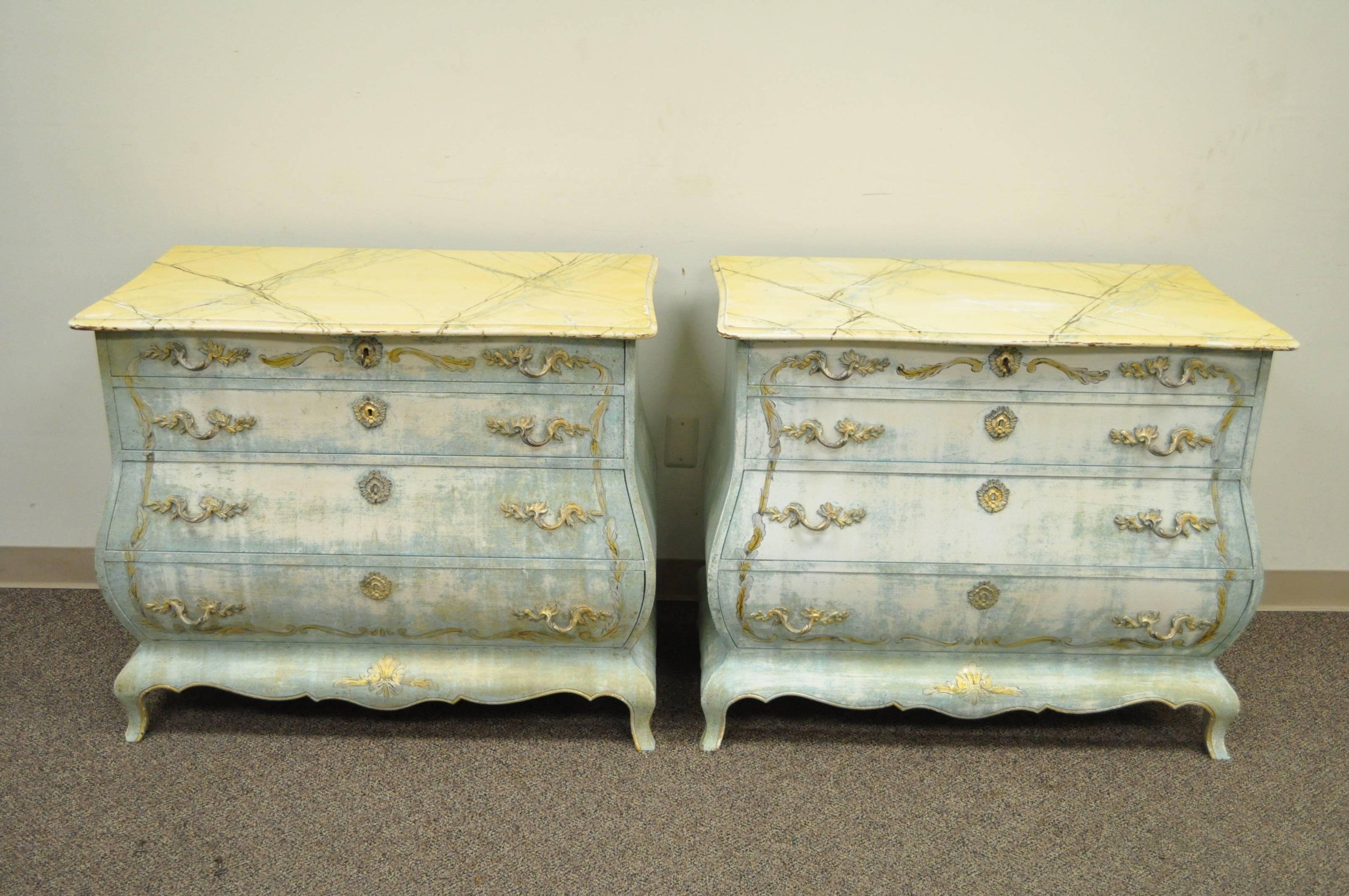 Impressive pair of vintage French Louis XV style bombe form commodes or bachelor chests. The pair features ornate brass hardware, faux marble painted tops, curvaceous bombe form, four drawers each, finished backs and an attractive blue washed /