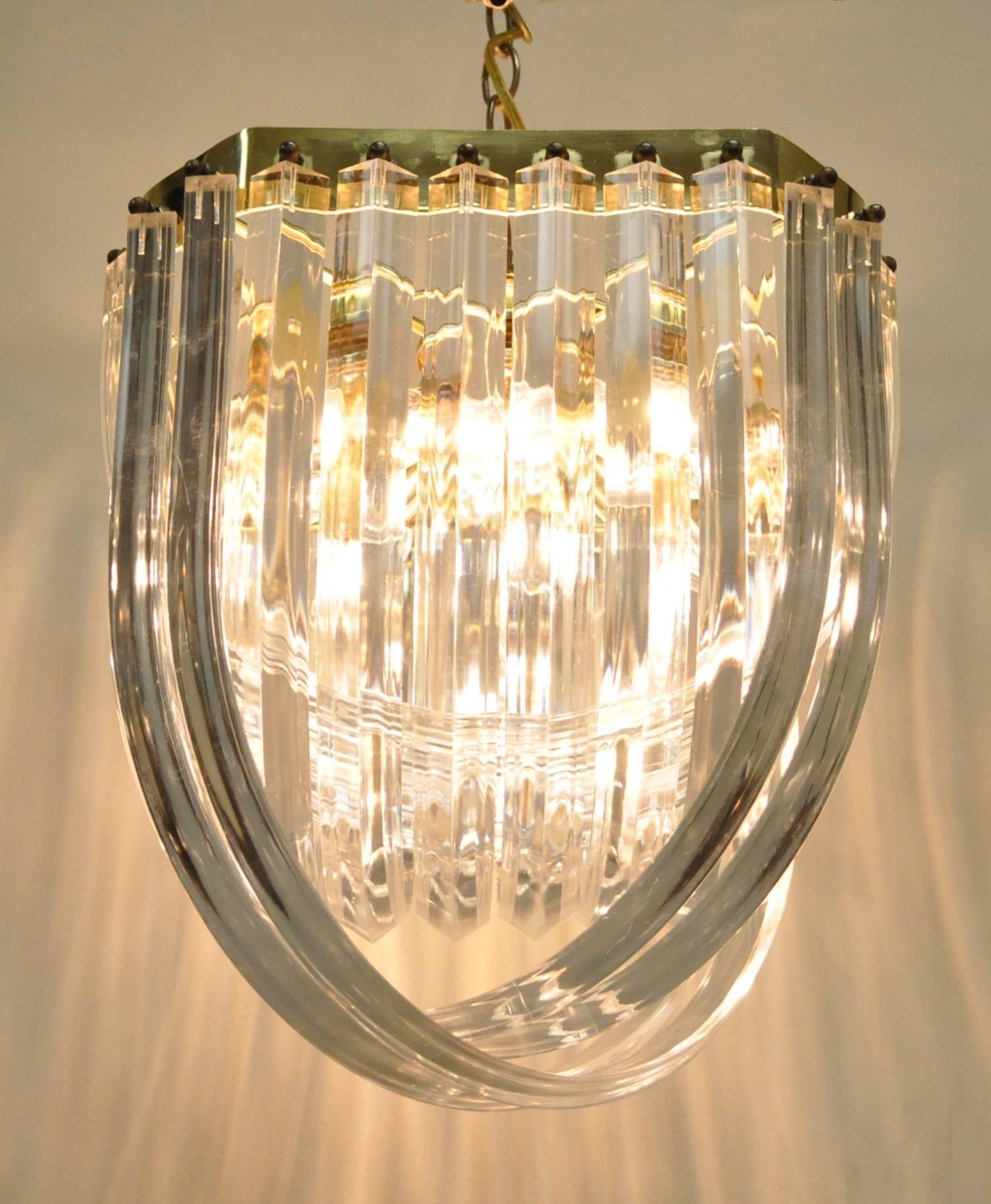 Vintage Mid Century Modern/Hollywood Regency Lucite 'Ribbon' Chandelier. Truly beautiful when lit up with the lucite refracting the light while the brass reflects it for an impressive amount of illumination. The chandelier has 8 lights total.