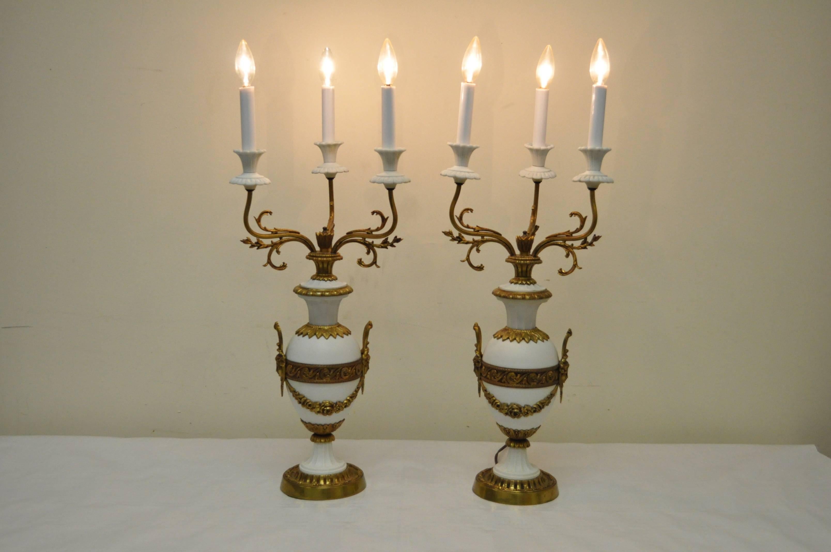 Elégante paire de lampes candélabres figuratives en porcelaine française et bronze dans le goût Louis XV / XVI. Les lampes présentent des draperies florales, des visages de jeunes filles, trois lumières chacune et une forme élégante. Marqué 