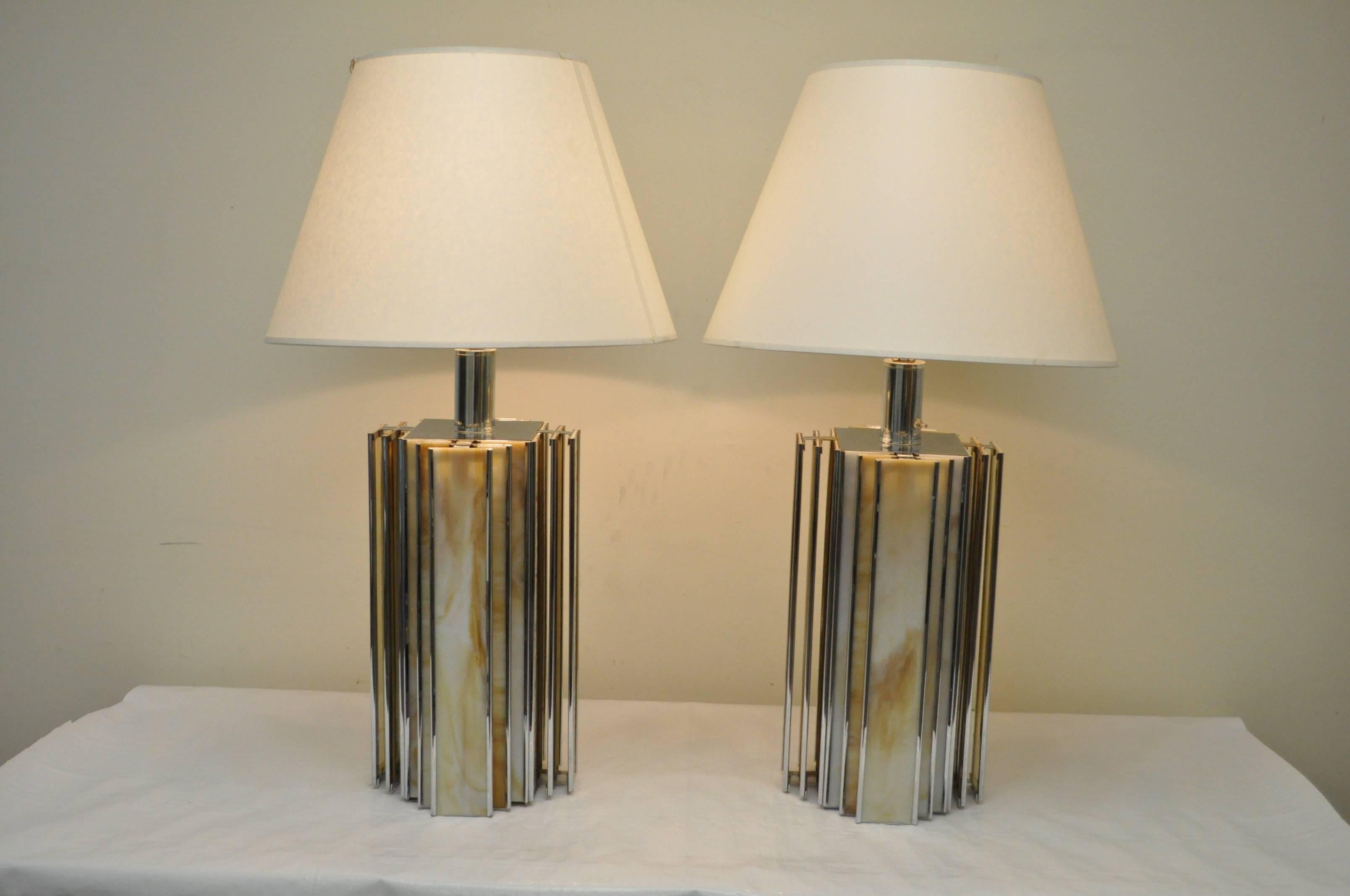 Pair of vintage chrome and slag glass table lamps. The lamps have a sleek modern design with Art Deco inspired geometric lines, and are constructed of chrome frames with richly colored slag glass inserts. The bases light up to illuminate the