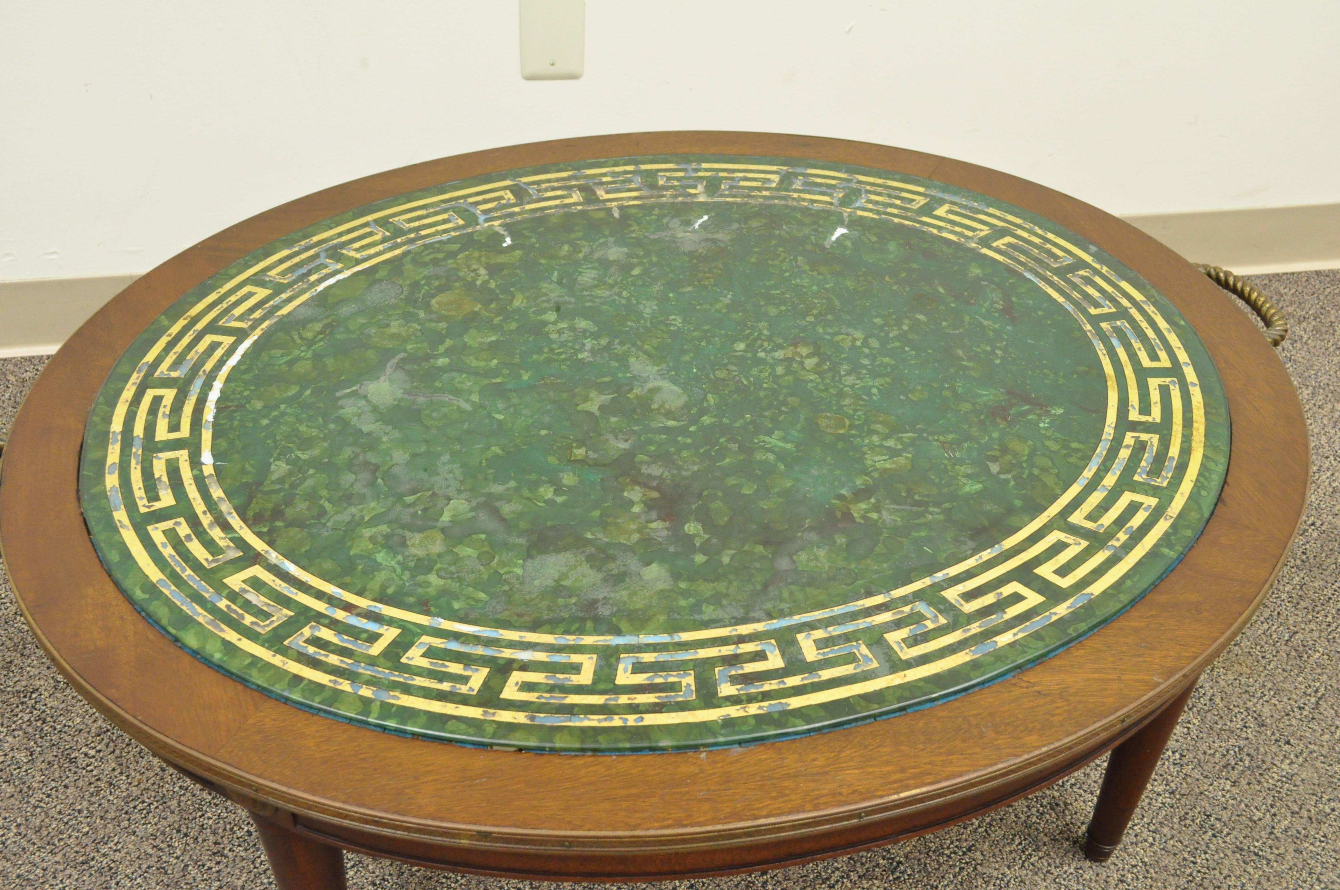 Unique vintage reverse decorated glass and mahogany oval coffee table with Greek key and faux malachite design to the top. Item features brass handles, decorative brass border and great neoclassical form.
