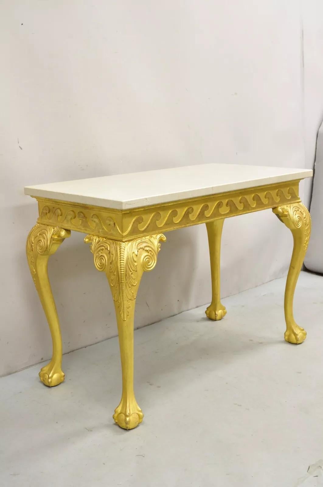 Mesa de salón consola de madera dorada dorada estilo Jorge II. El artículo presenta una base tallada decorada con volutas en los 4 lados, una gruesa encimera de mármol, un acabado dorado envejecido, patas cabriolé talladas y pies de bola y garra.