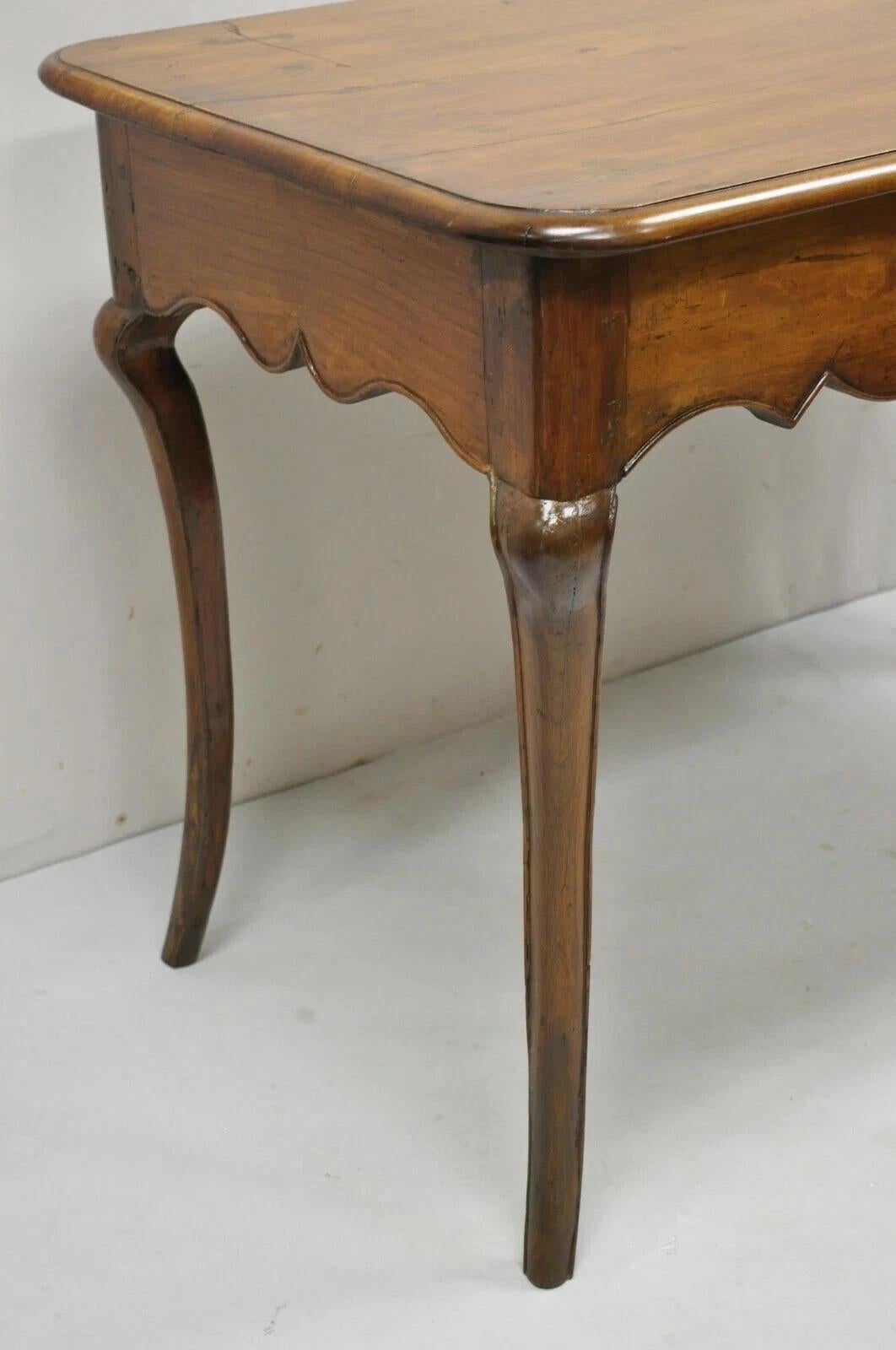 Antique French Provincial Carved Cherry Wood Saber Leg Italian Desk Console Table. Item features solid wood construction, beautiful wood grain, distressed finish, shapely saber legs, and quality Italian craftsmanship. Circa Late 19th Century.