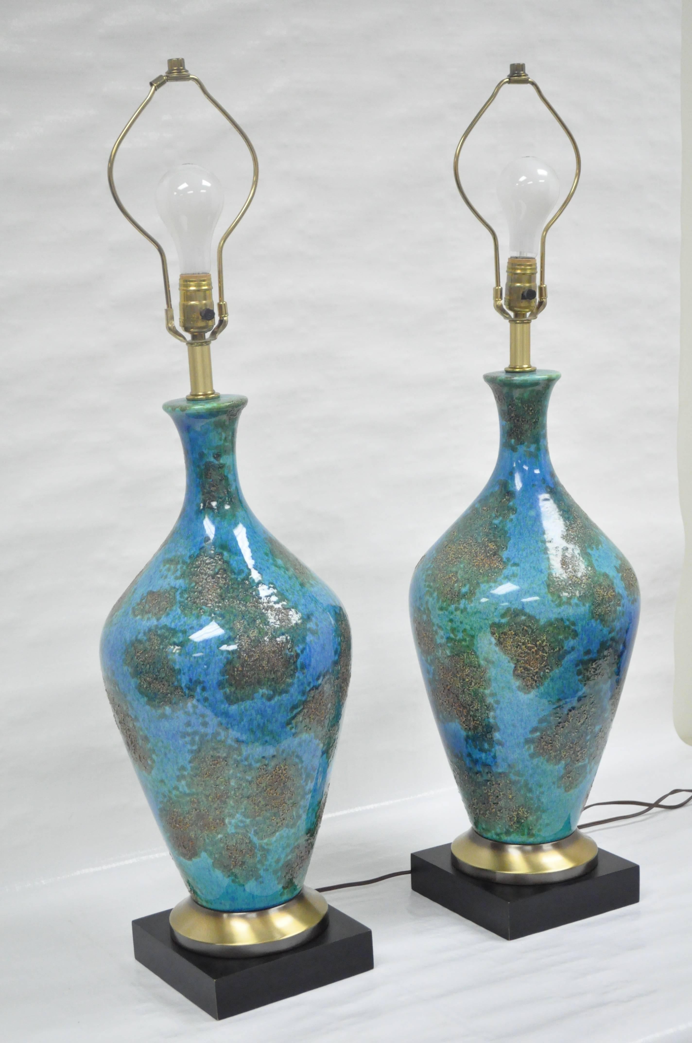 Remarkable pair of quality vintage blue glazed ceramic sculptural table lamps. The pair features glazed ceramic uppers resting on brass and painted wood bases with three-way sockets.