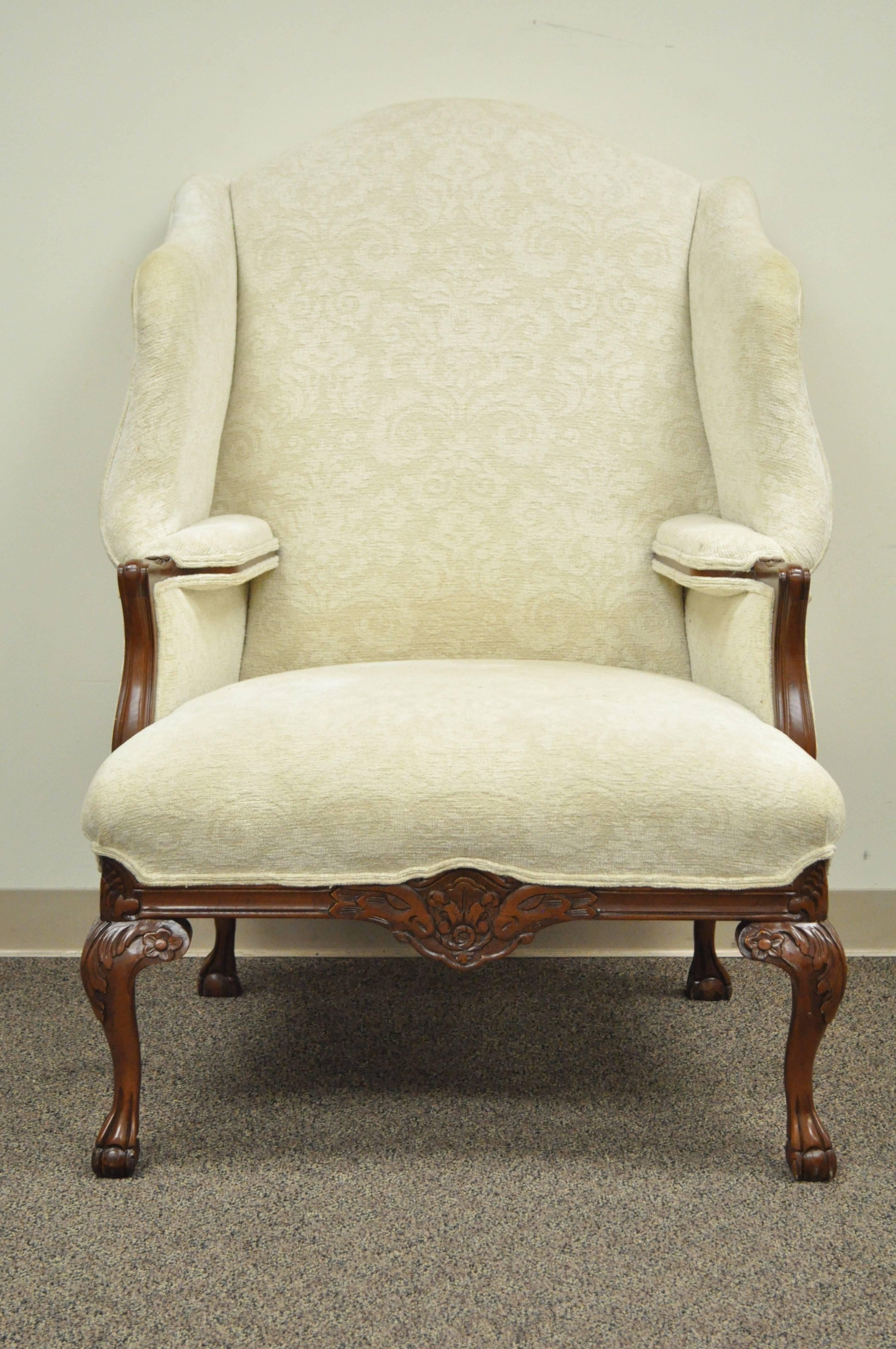 High quality solid carved mahogany Chippendale style wing back bergere armchair. Item features an exaggerated shapely winged back, interior armrests with exposed wood supports, four ball and claw feet, carved knees, carved lower rail, stately size