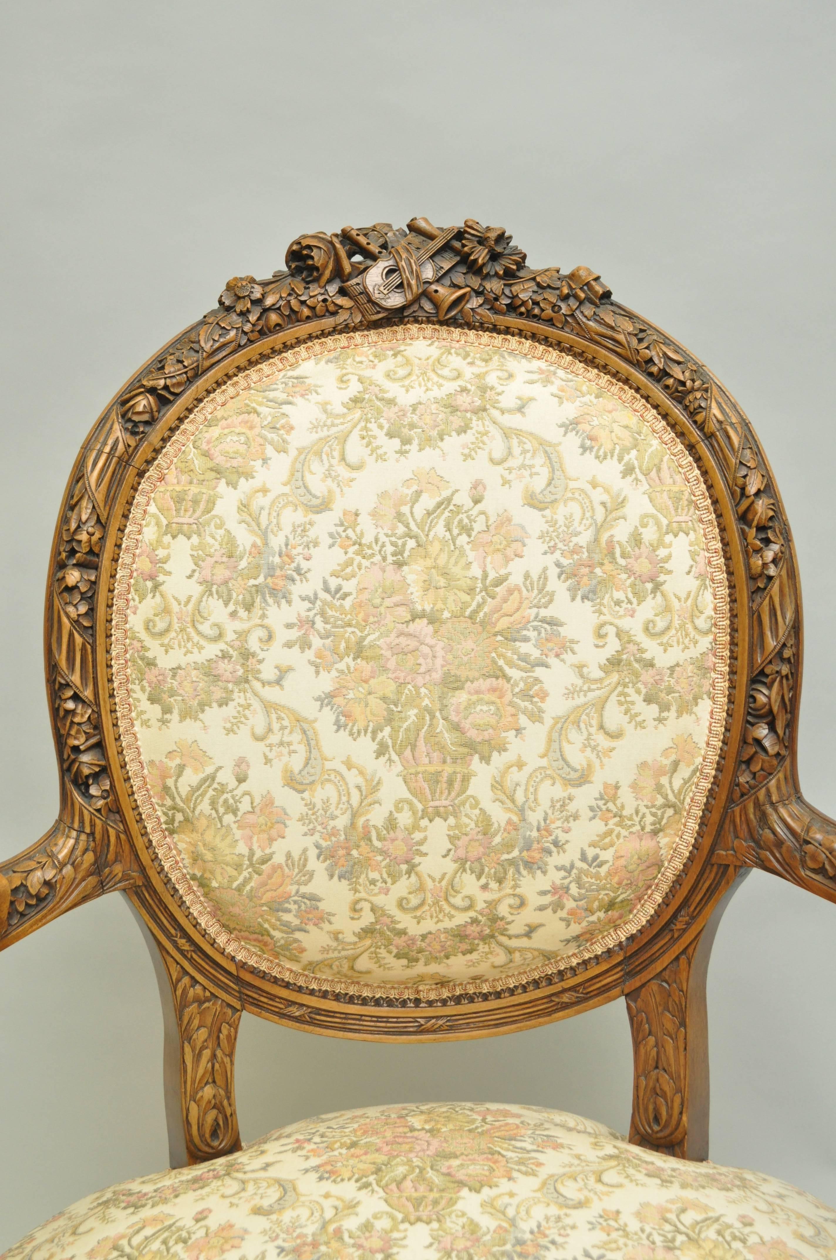 Remarkable early 1900s, French fauteuil in the Louis XVI taste. Item features ornate and fine carvings to the solid walnut frame including musical instruments at the crest. Chair further features a round medallion back, open arms and reeded and