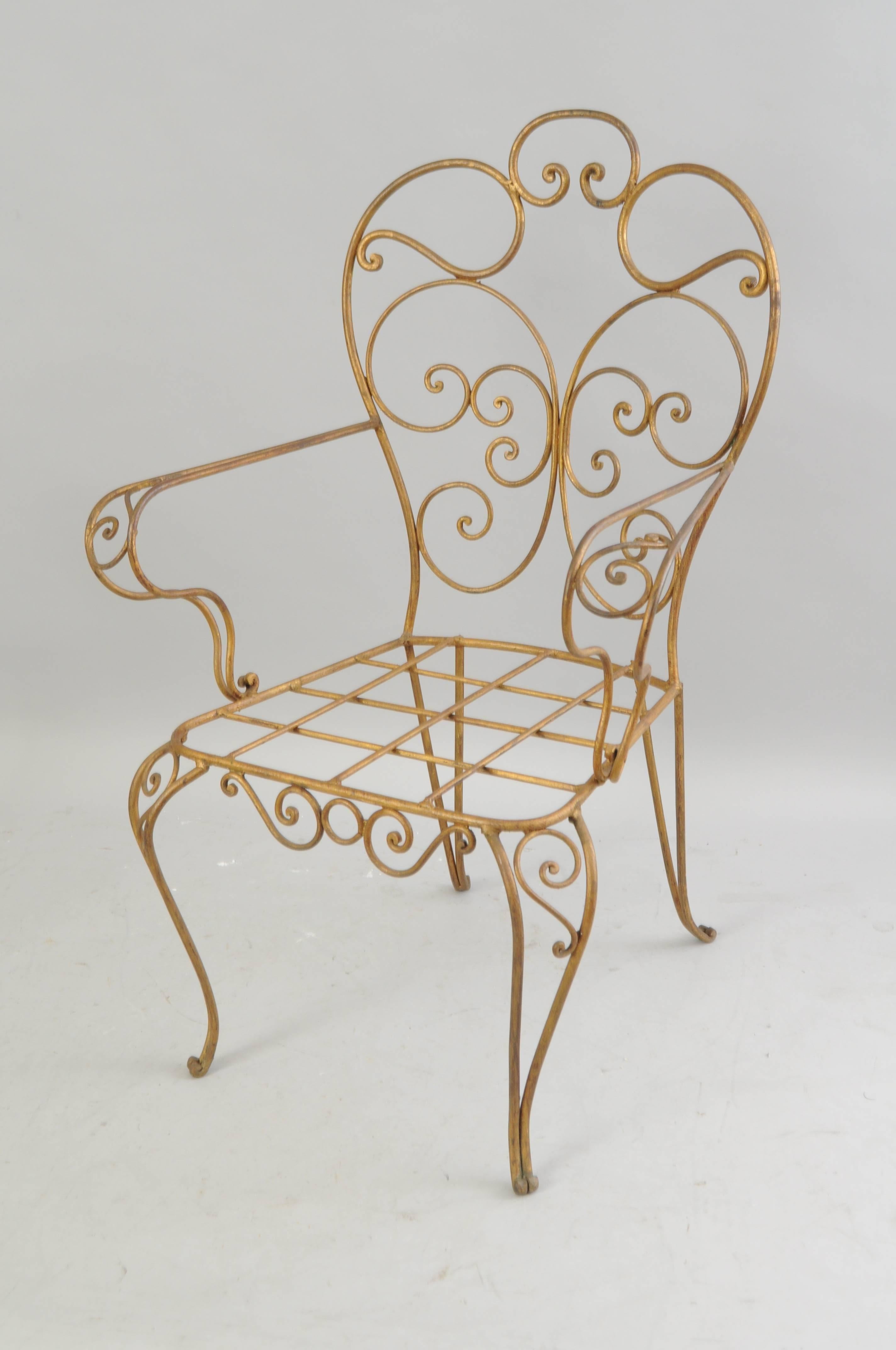 Set of four vintage Italian gold gilt iron arm chairs. Chairs feature ornate scroll-work frames, cabriole legs, cross thatched seats, and beautiful antiqued gold gilt finish to the iron frames. Great to add loose seat cushions.
