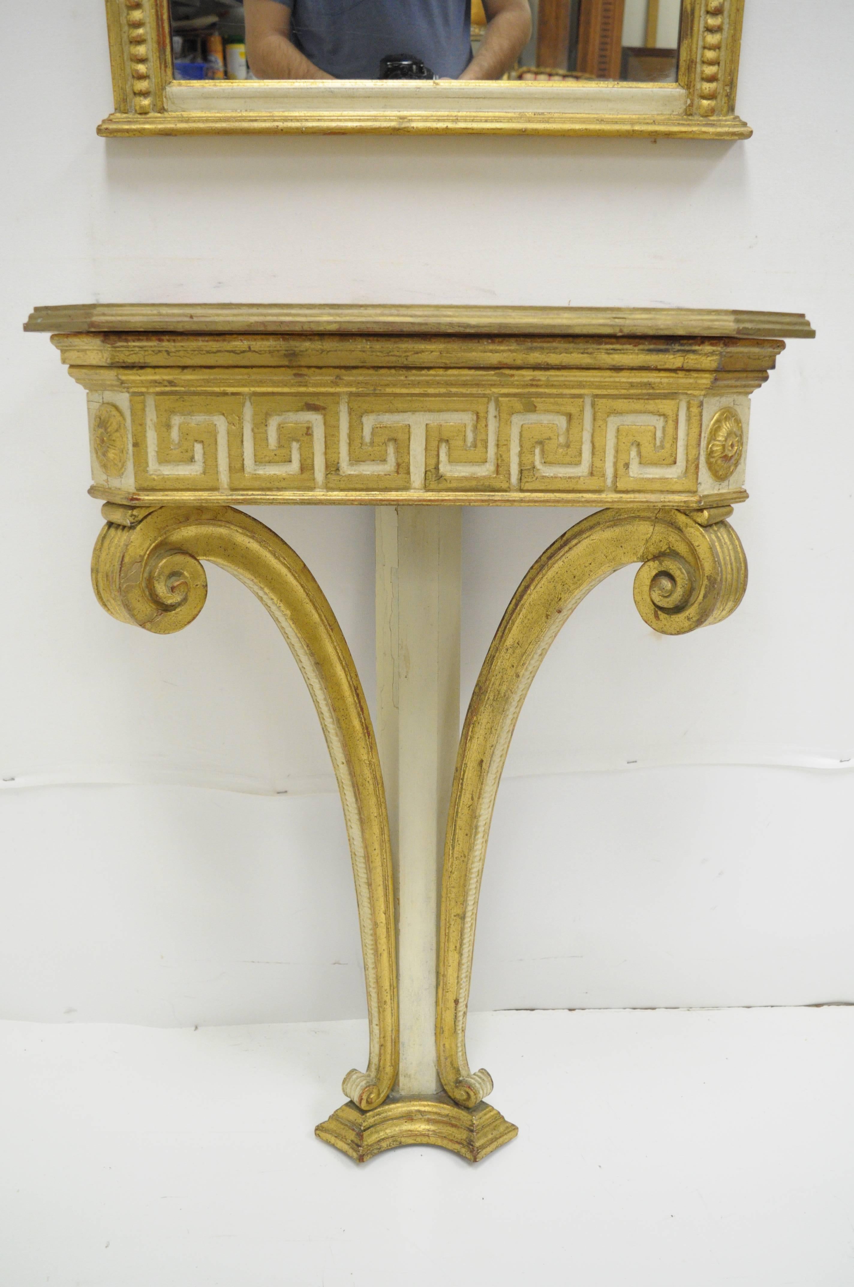 Vintage, early 20th century, Italian neoclassical style gold giltwood Greek key design wall mount small console table and rectangular mirror. Item features a carved wood gold gilt frame mirror with an attractive antiqued cream and gold finish. The