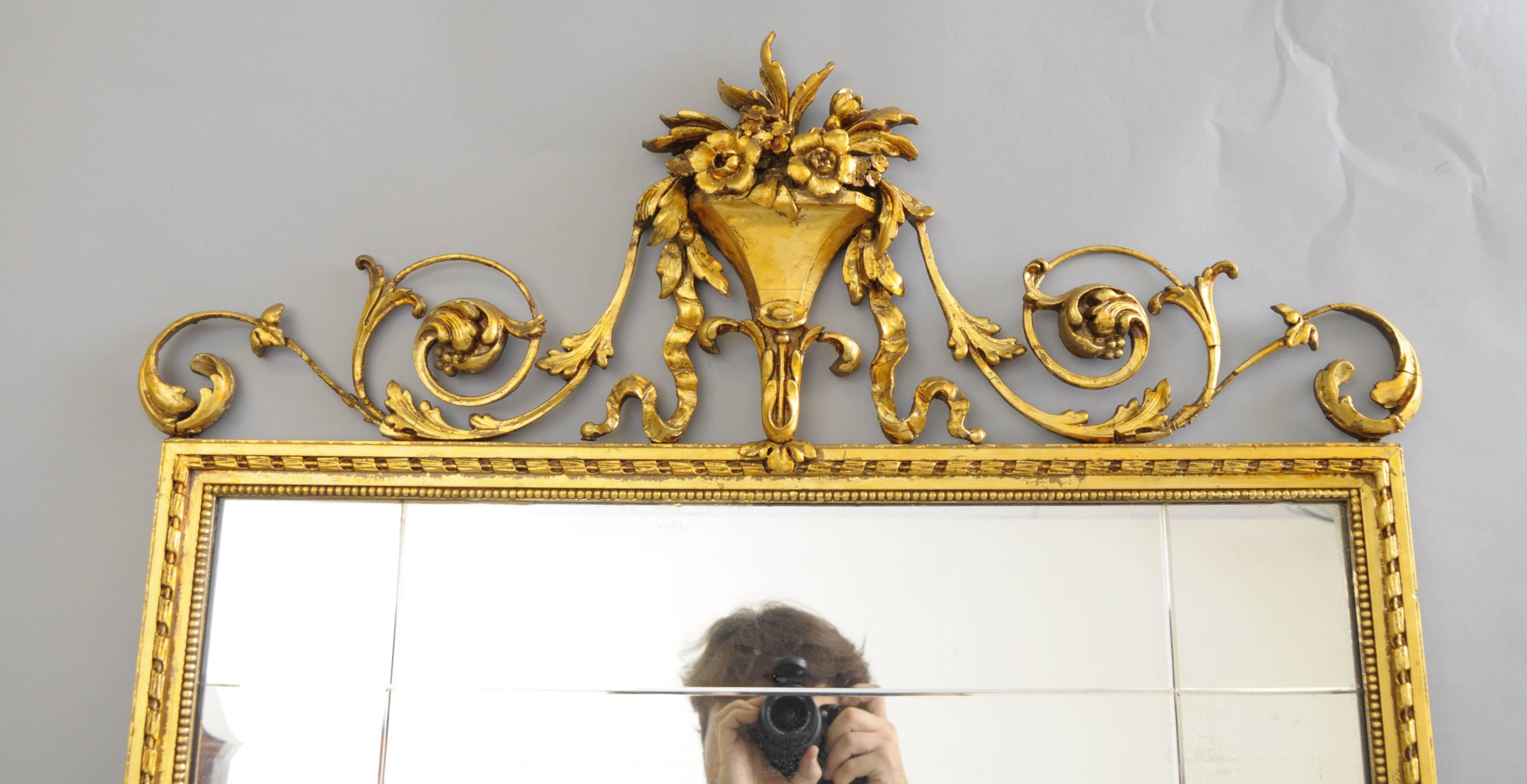Early 20th Century carved gold giltwood and gesso English Robert Adam style rectangular wall mirror. Item features an iron and gesso blooming floral bouquet with draping acanthus leaves and bell flowers. The giltwood and gold leaf frame displays