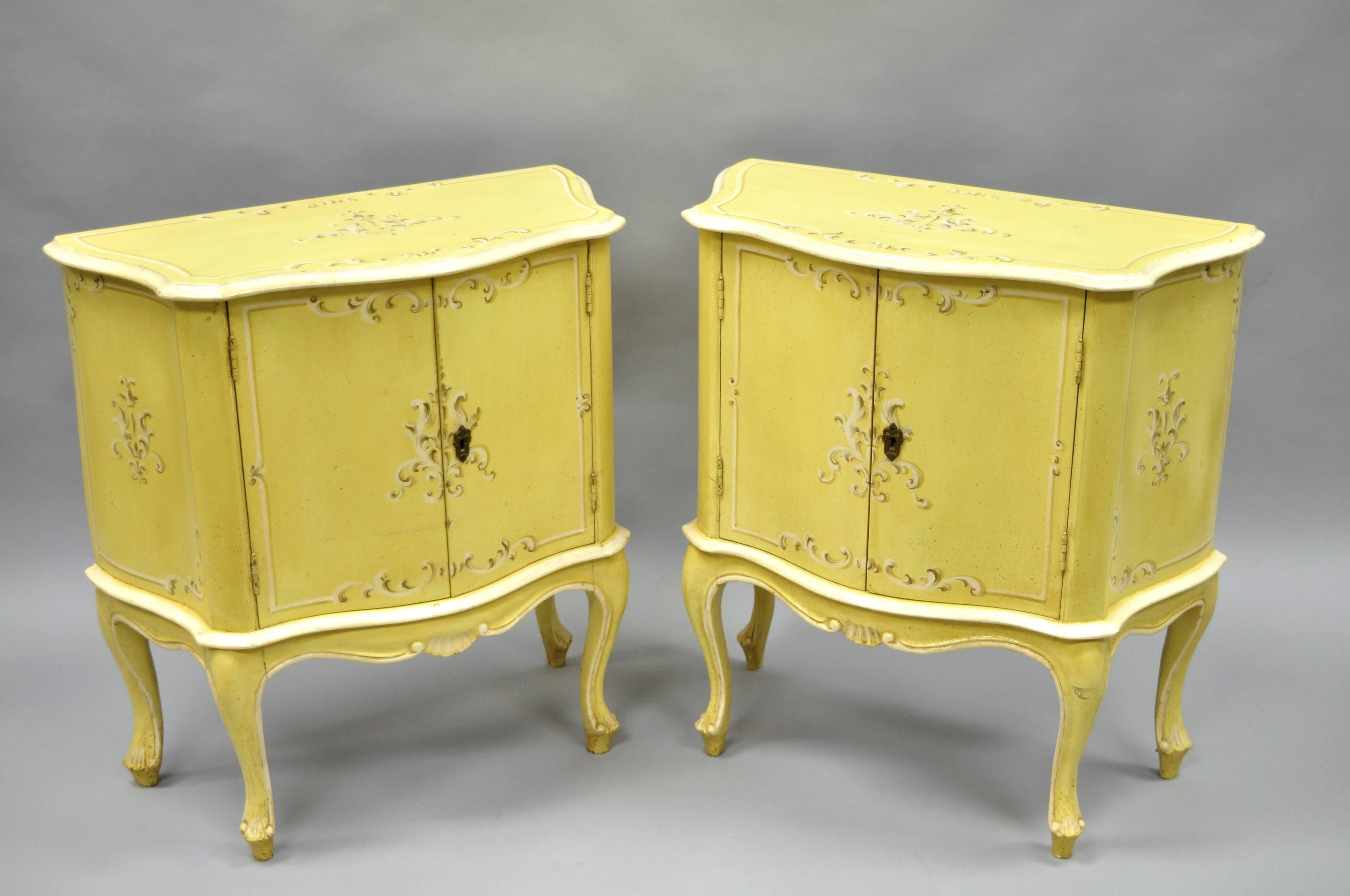 Pair of vintage petite Italian Florentine / Venetian yellow painted bombe commodes / bedside tables. This adorable pair of tables features an antiqued yellow painted finish with floral details to the face, sides, and tops. Chests further feature an