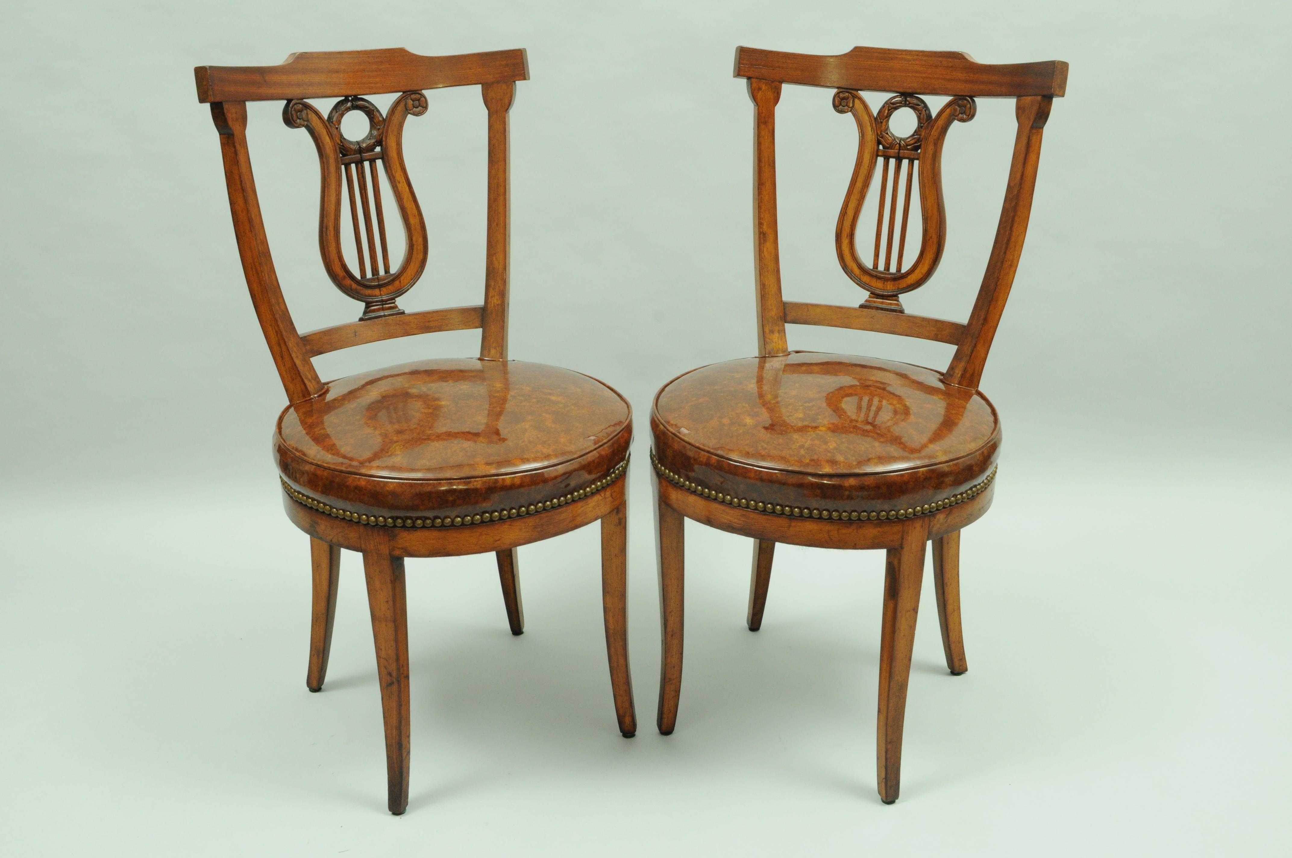 Set of four vintage lyre back regency or neoclassical style side chairs. Chairs feature; faux tortoise shell brown vinyl upholstered round seats, shapely klismos legs, original manufacturers distressed or antiqued finish to the solid wood frames,