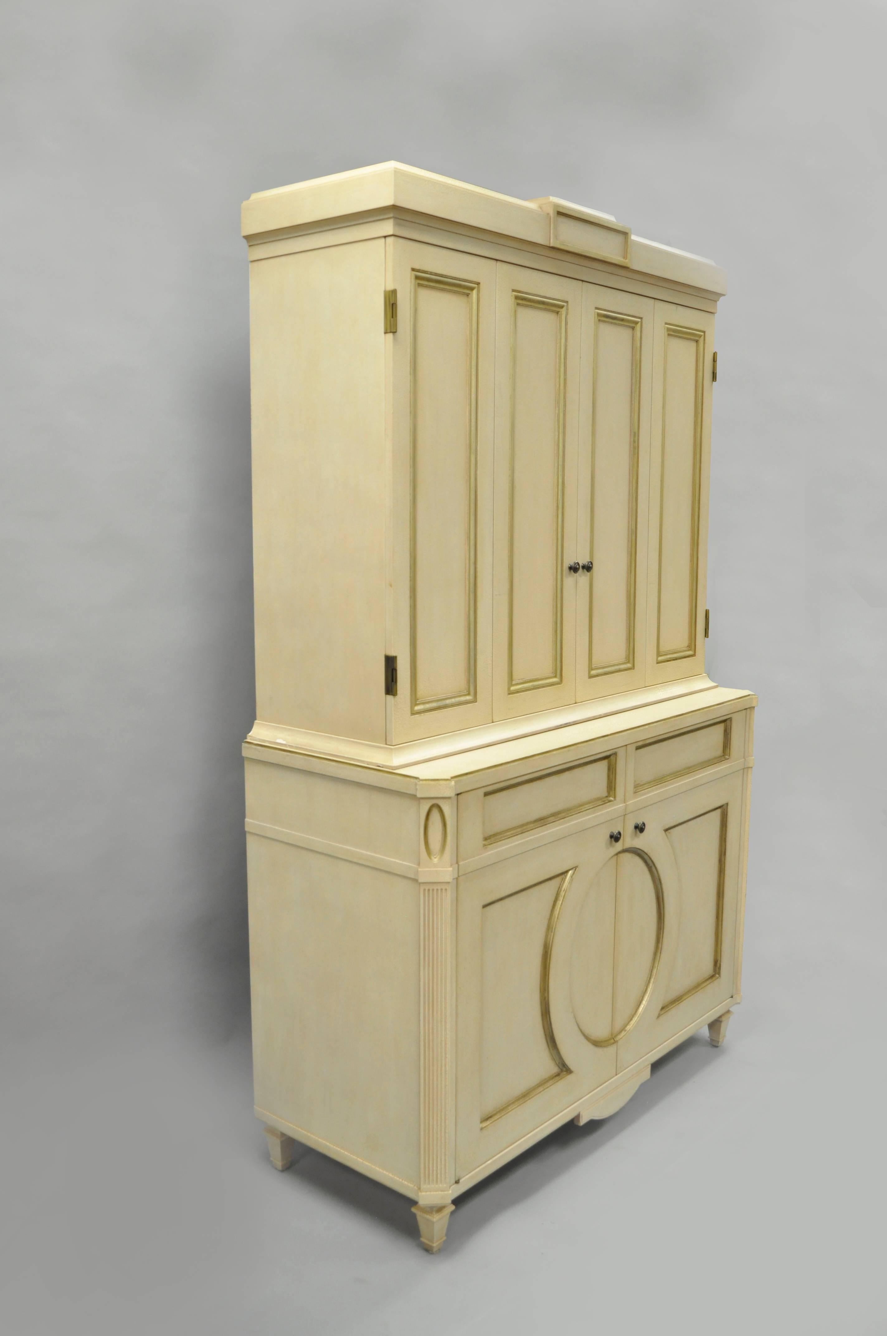 Large and impressive late 20th century custom-made cream and gold distress painted cabinet by Decca in the French Louis XVI Directoire/neoclassical style. Item features a heavy two part construction with crackle distress painted cream finish with
