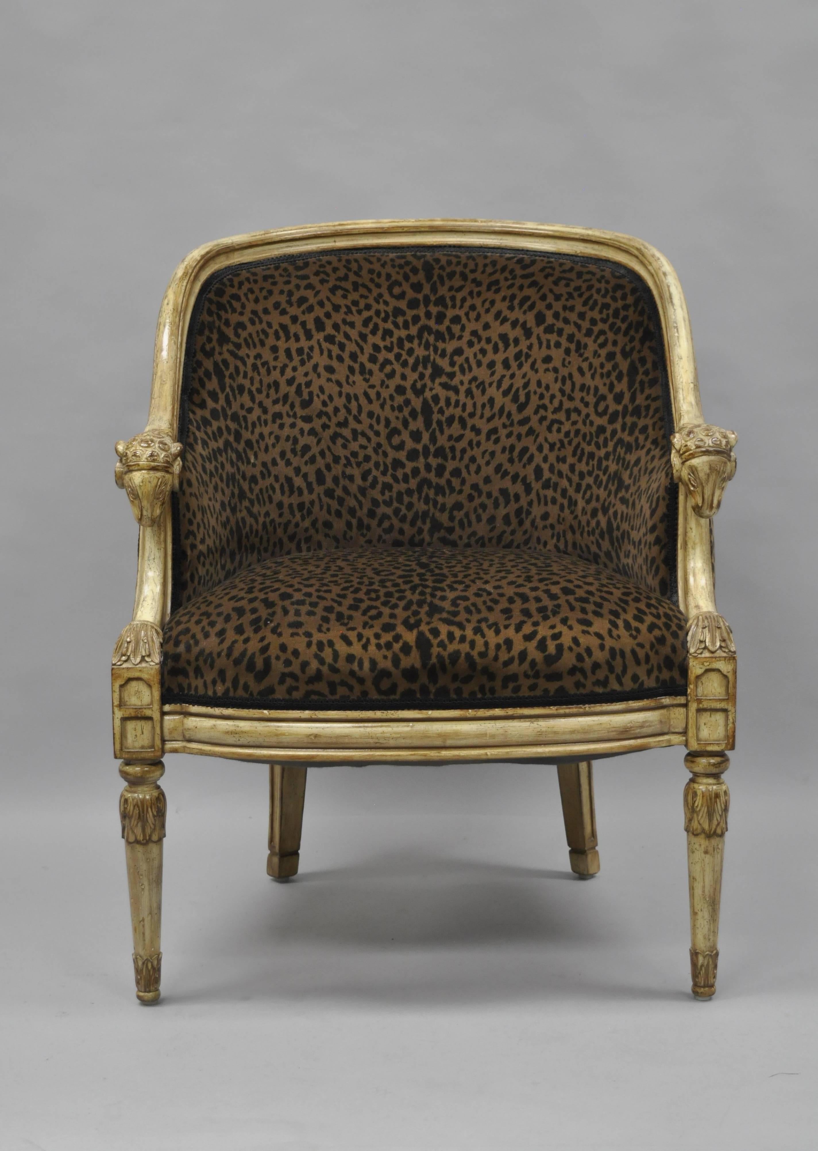 Late 20th century barrel back ram's head bergere chair with cheetah fabric in the neoclassical style. Item features a solid carved wood frame, cream distress painted finish, comfortable barrel form back, Ram's head armrests, tapered cabriole legs,