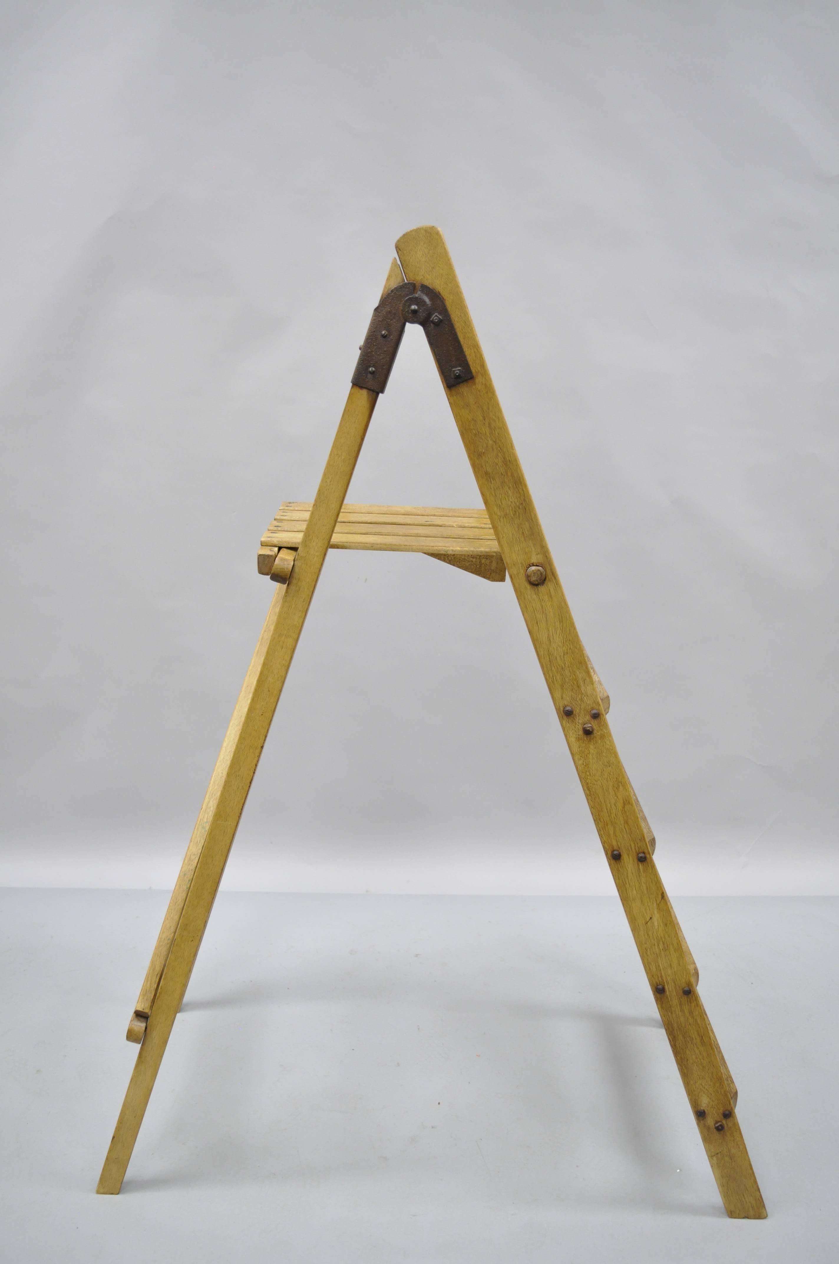 Antique four step a-frame wooden ladder with shelf. Item features solid wood construction, beautiful wood grain, quality craftsmanship, four steps, metal hardware, wonderful patina, and upper self. Measurements: 55