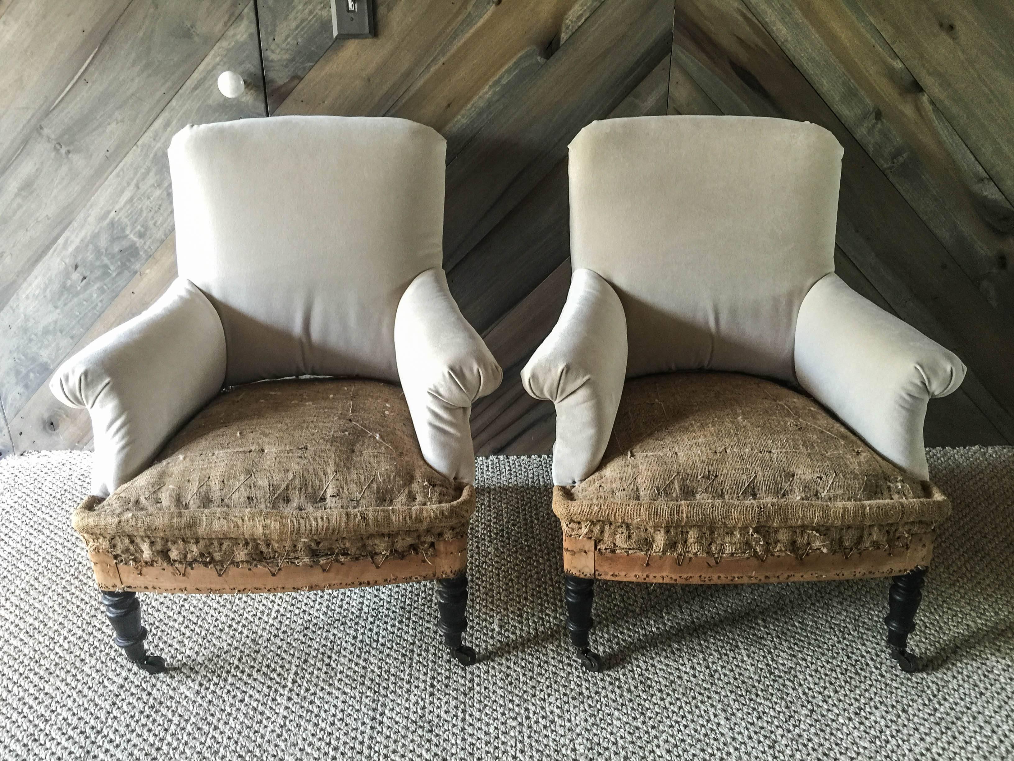 Pair of French salon chairs newly upholstered in cement cotton velvet leaving the sides and back uncovered to highlight authenticity and age. Ebonized turned legs with brass casters.