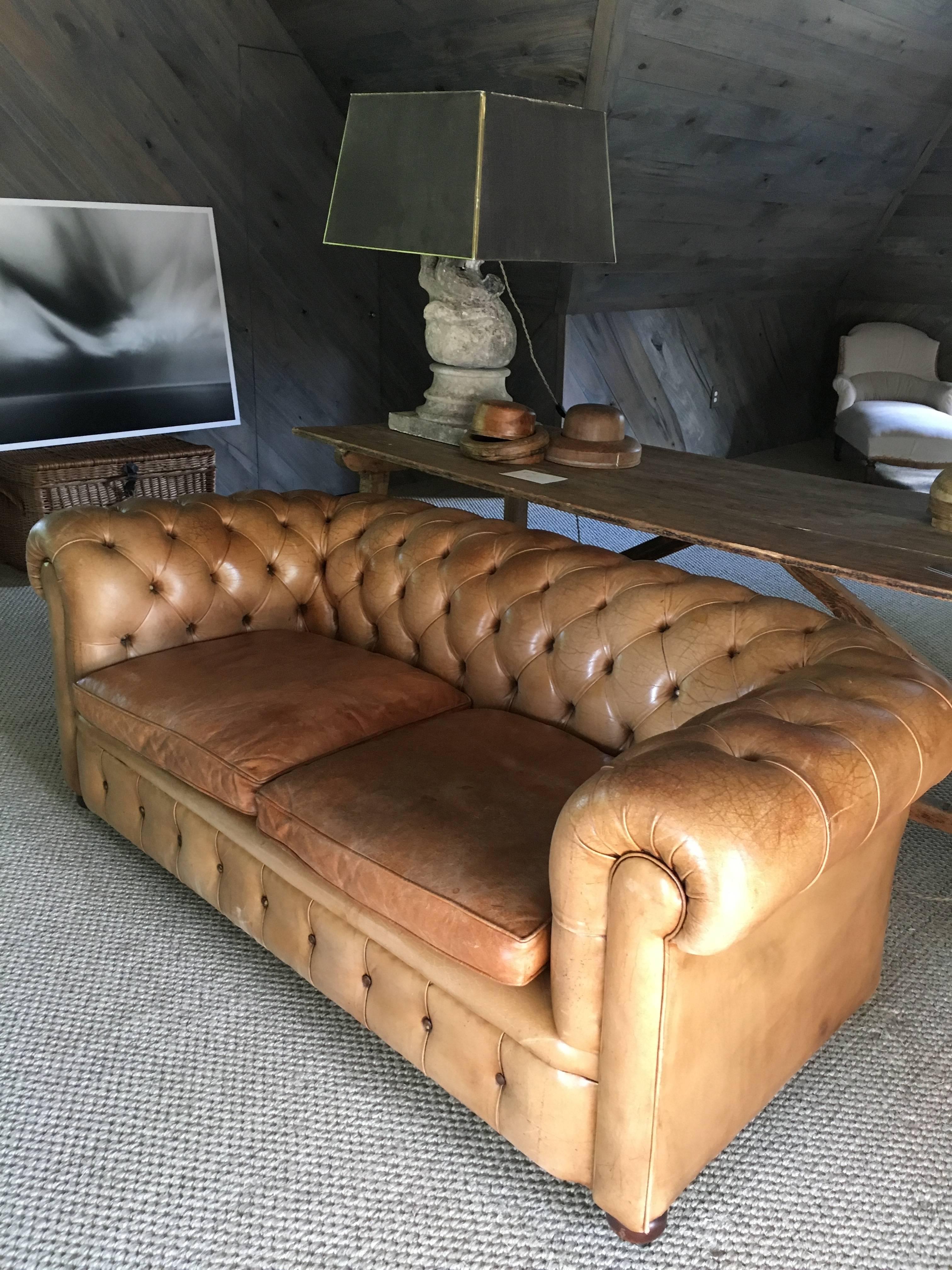 French leather Chesterfield sofa, circa 1900. The tufted design is attributed to an 18th century Earl of Chesterfield, who wished to provide comfortable seating to guests that would not wrinkle their clothes. Amazing sun faded patina on the caramel