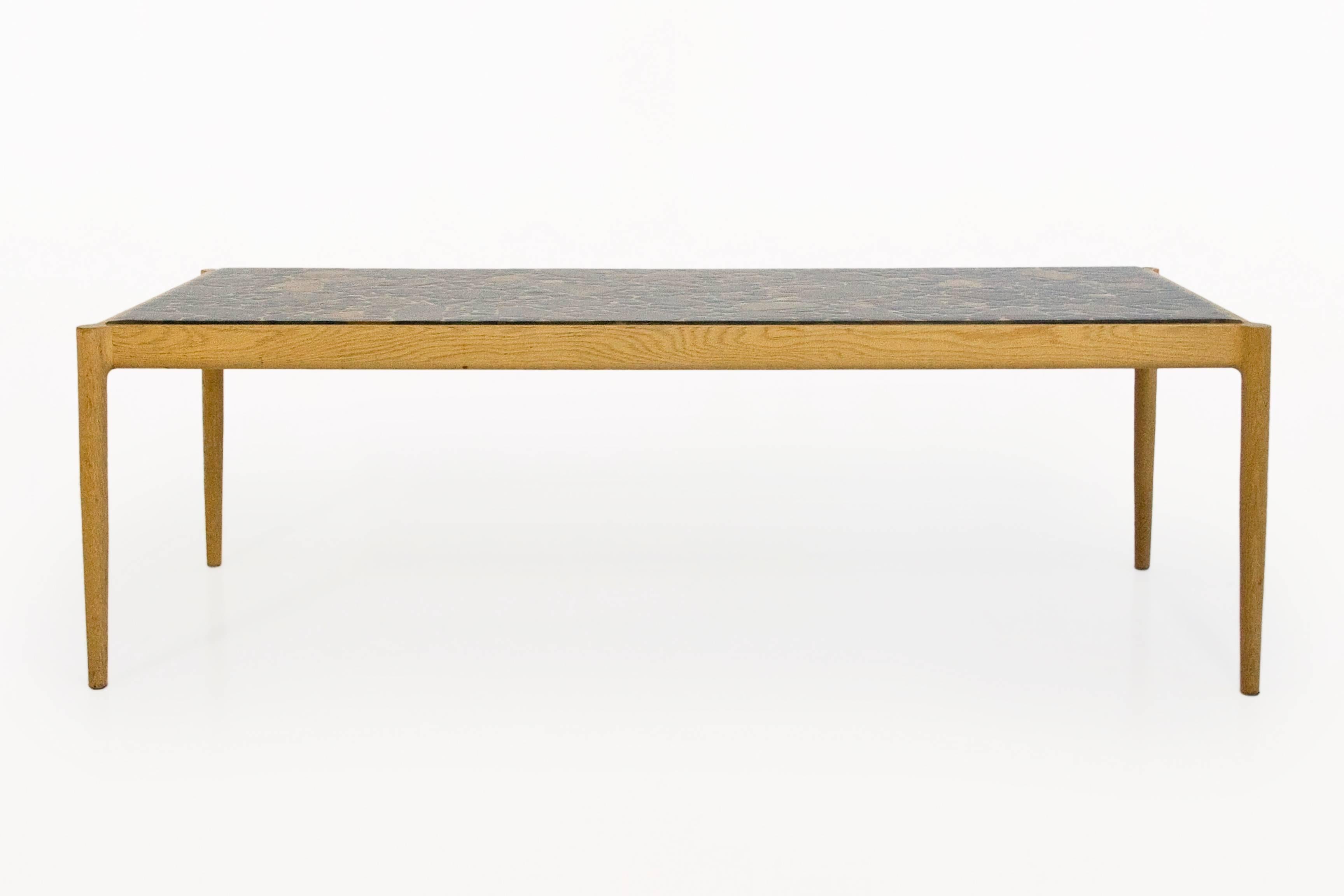 IB Kofod-Larsen (1921-2003)  coffee table by Seffle Möbelfabrik,
coffee table in elm with resin and stone top, stamped,
with pebbles inclusions, edited by AB Seffle,
circa 1960, Sweden.
Measures: Height 48 cm, width 152 cm, depth 61 cm.