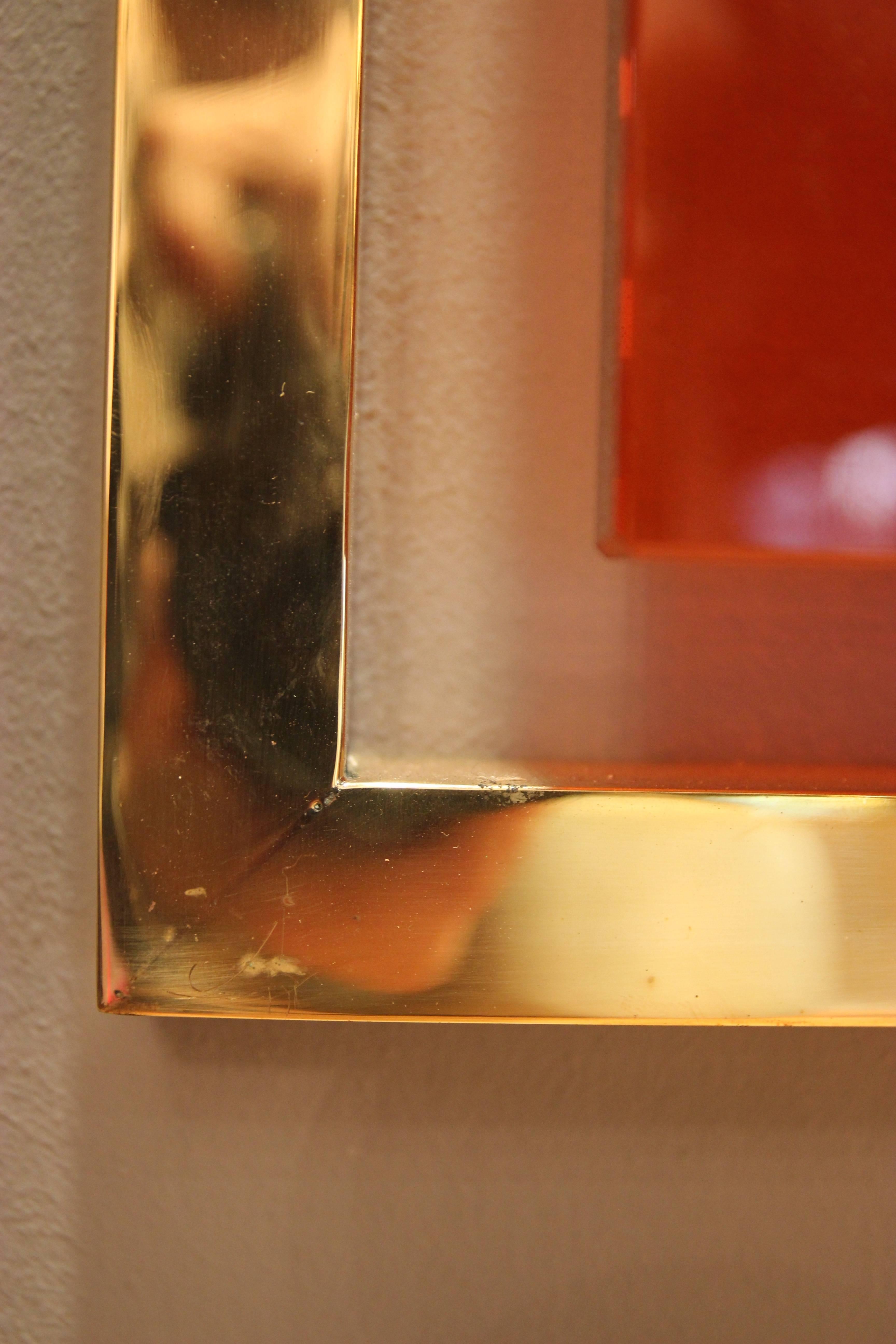 Wall mirror,
Gold-plated brass and orange glass,
Circa 2010, Italy.
Height: 112 cm, width 80 cm, depth: 8 cm.

