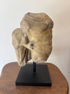 Fragment eines Flachreliefs, das einen jugendlichen Torso zeigt, der sich an ein architektonisches Element lehnt.
