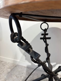 Small wrought-iron pedestal table with a base featuring marine anchors.