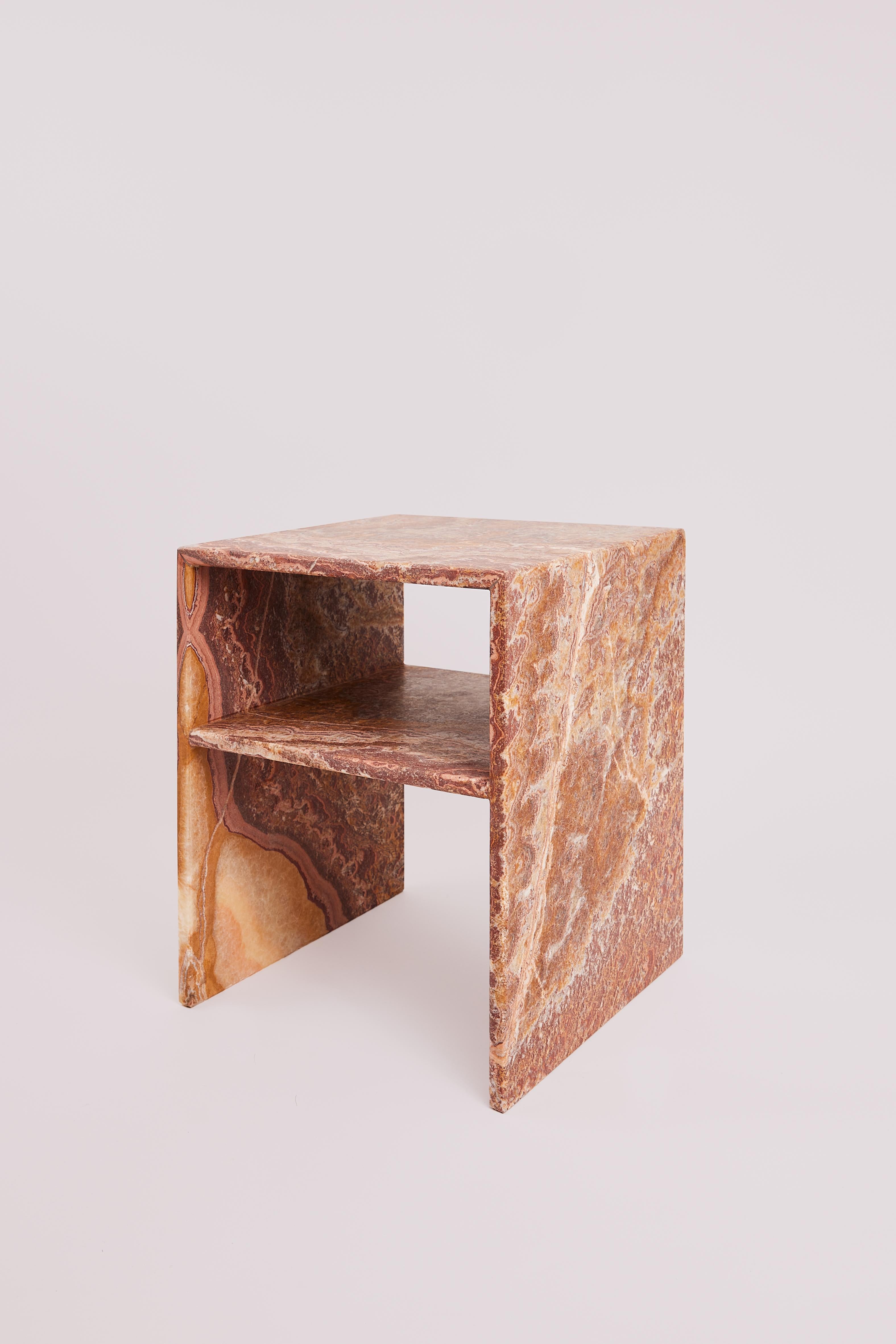 This collectible side table by Studio Gaïa is sculpted from rare red onyx, a semi-precious stone extracted from the mountainous quarries of Mexico. Richly veined in tones of terracotta, burnt sienna, rose, and warm cream, the stone's intricate