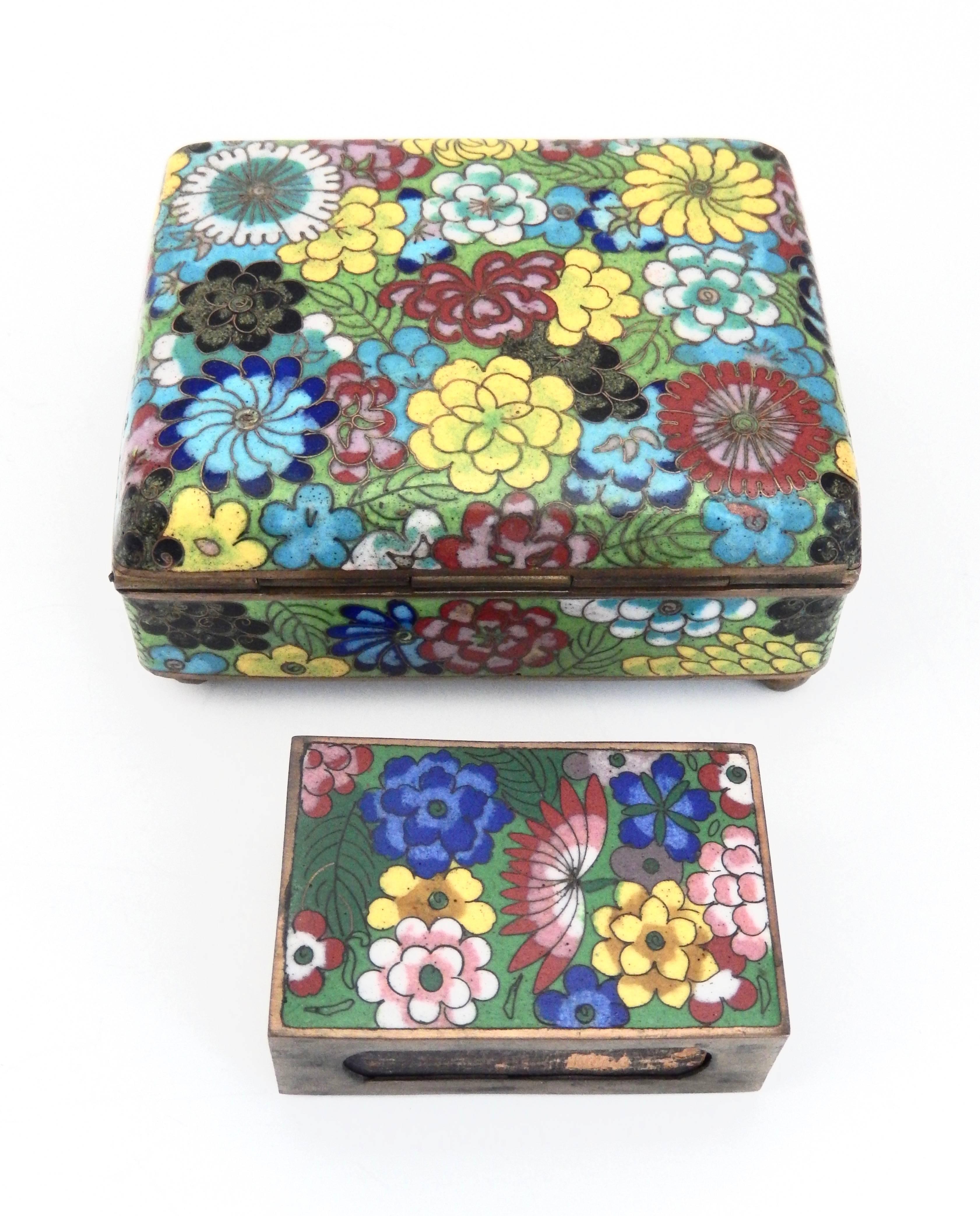 A multicolored, lidded box and match holder with an enameled floral pattern.
The intricate design resembles a field of stylized flowers and leaves consisting of beautifully, colored enamels. 

Measurement is for footed box. 

Match holder