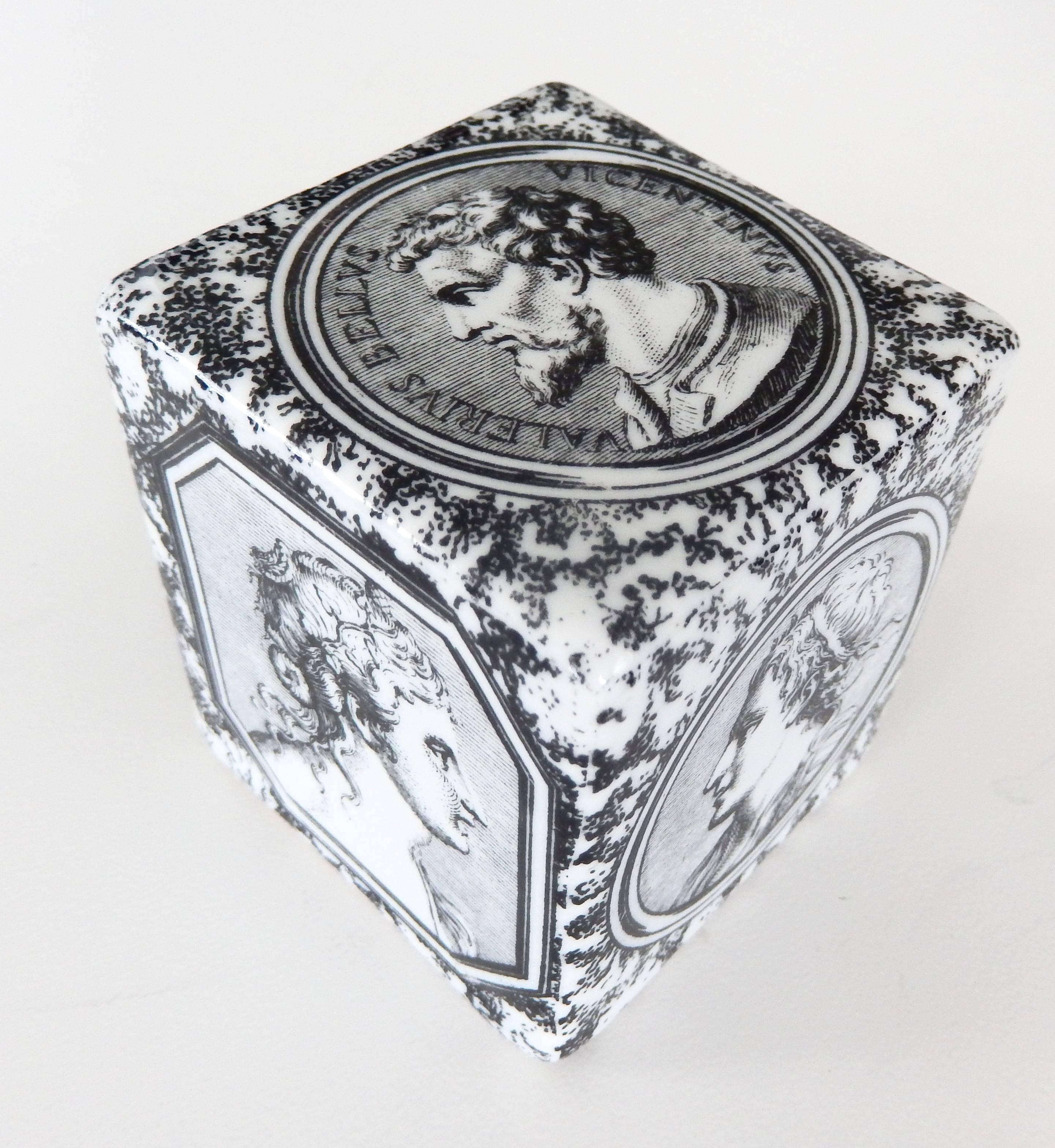 A ceramic cube paperweight by Piero Fornasetti with classical portraits on a faux marble ground. A great example of Fornasetti's innovative graphic design and recurrent neoclassical motifs. Embossed signature on base.