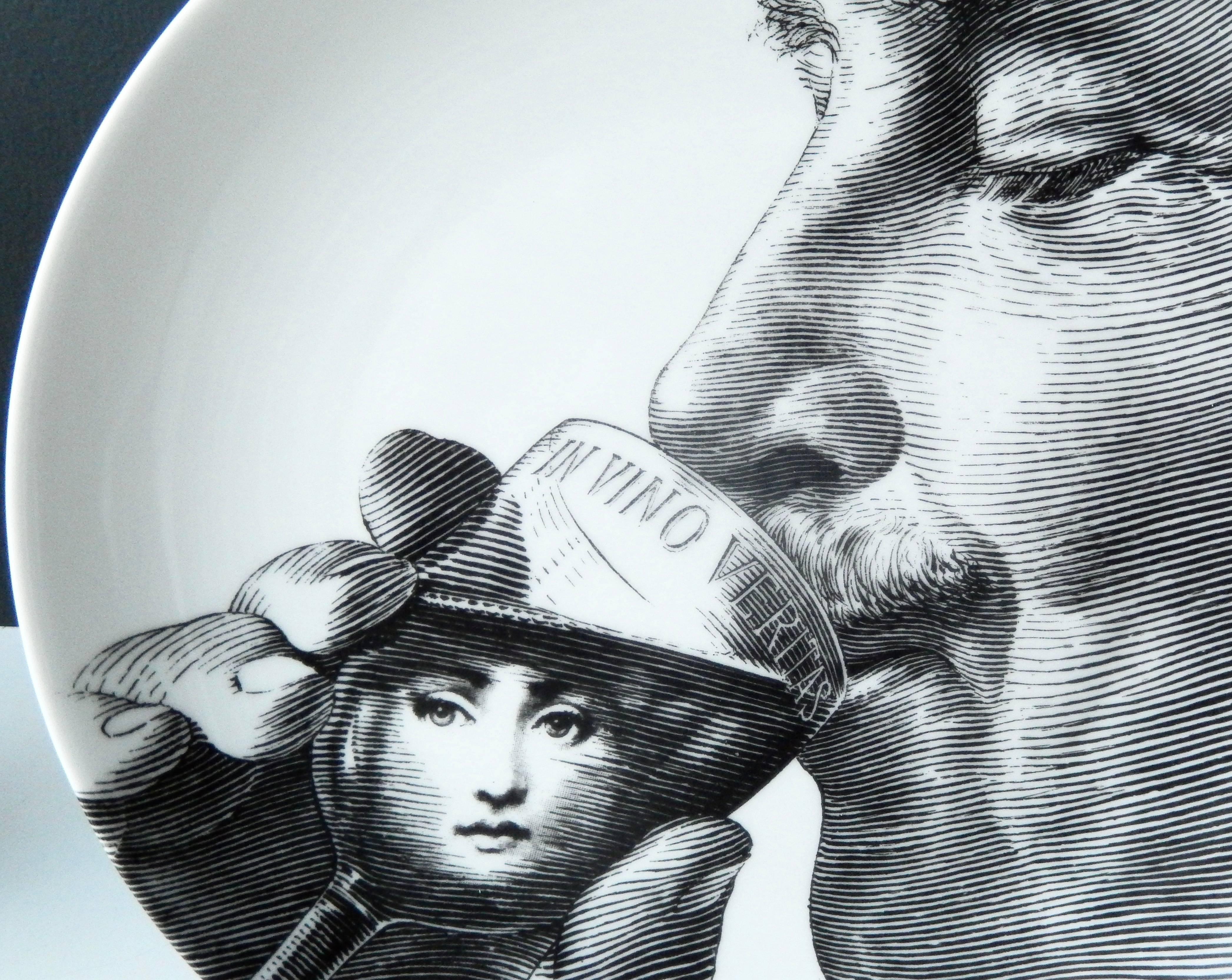 A witty, self-portrait plate of Piero Fornasetti drinking wine from a glass that reads "In Vino Veritas" (in wine there is truth). The surreal face of his muse, Lina Cavalieri, is depicted gazing at the viewer from within the glass. Among