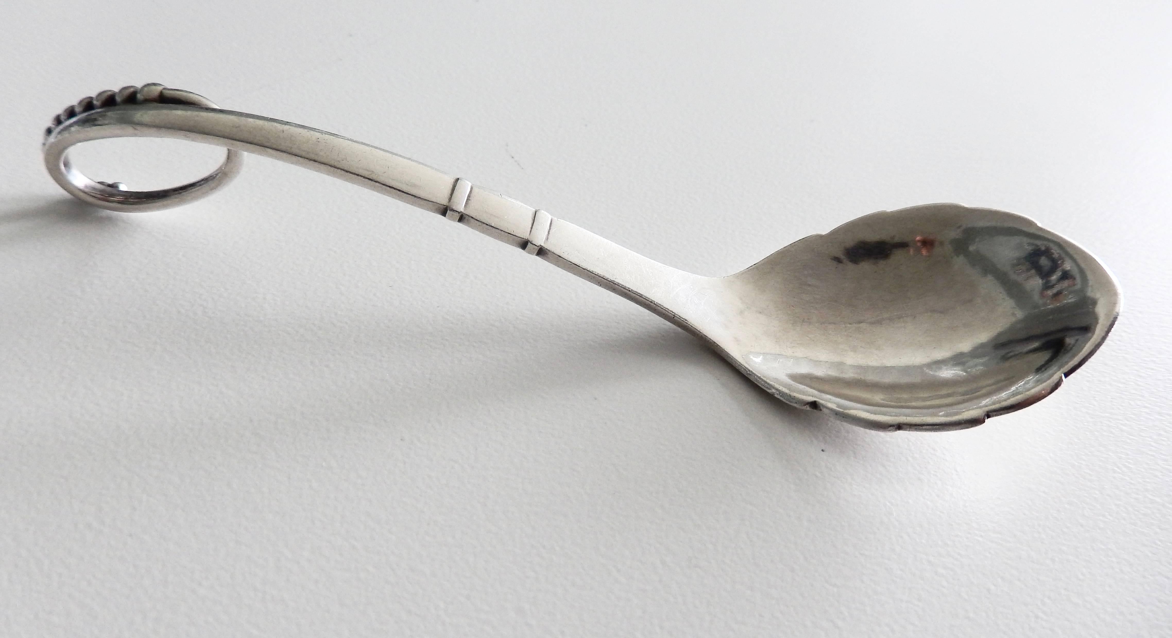 A beautiful example of Jensen's scalloped, sterling silver sugar spoon, #41, with a curved handle. An elegant, graceful form with fine detailing. Marked.