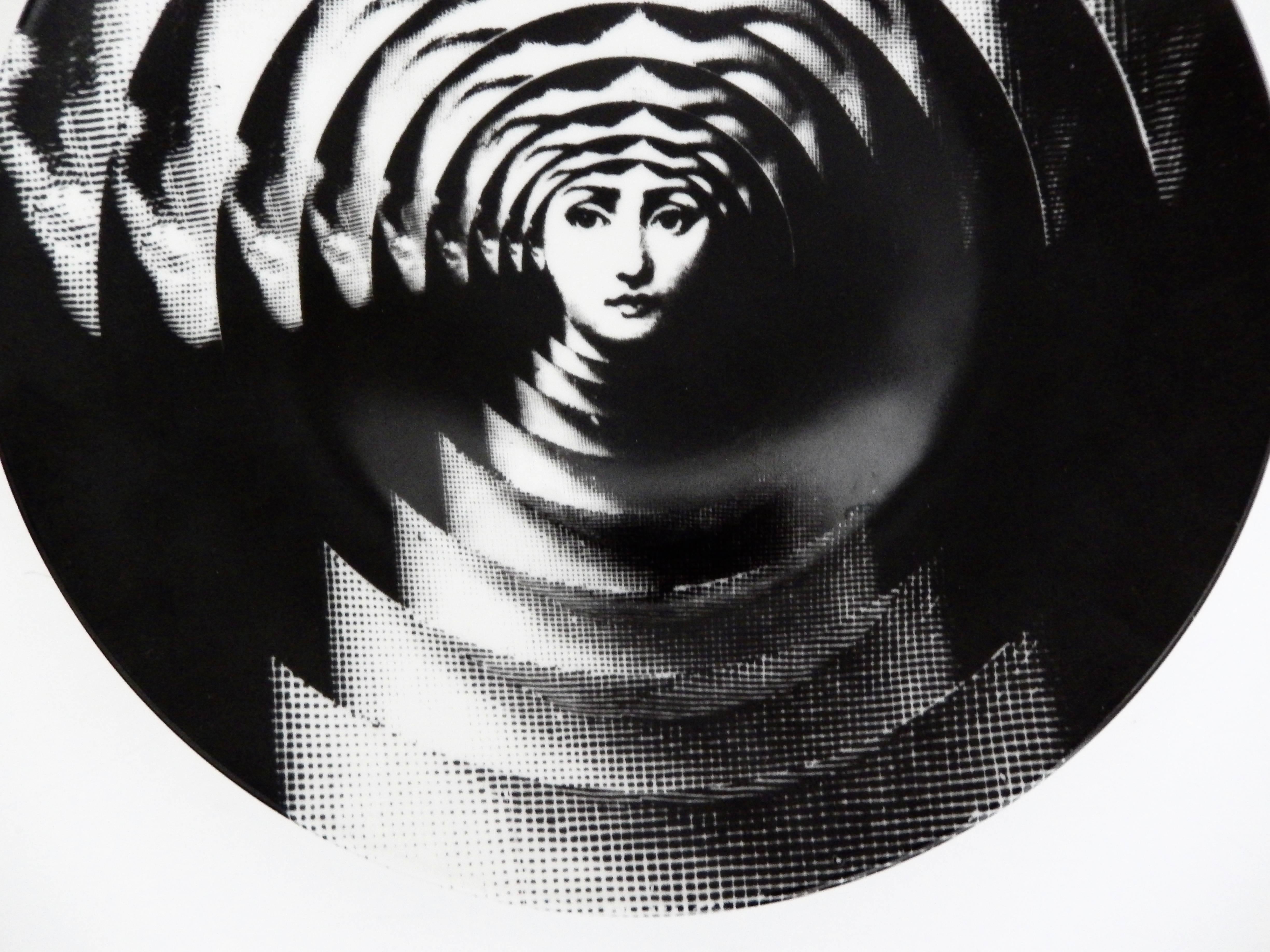 A porcelain plate with a mesmerizing Op Art design by Piero Fornasetti (1913-1988). He depicts his muse, Lina Cavalieri, in a series of overlapping plates, creating the illusion of movement.
Very strong graphic design. Marked: Rosenthal Germany.